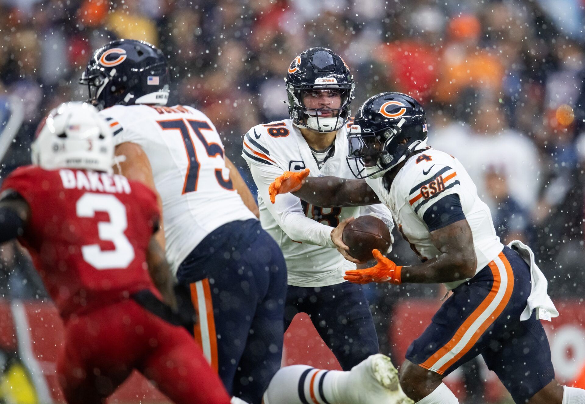 Chicago Bears quarterback Caleb Williams (18) hands the ball off to running back D'Andre Swift (4) as hail and rain fall against the Arizona Cardinals in the first half at State Farm Stadium.