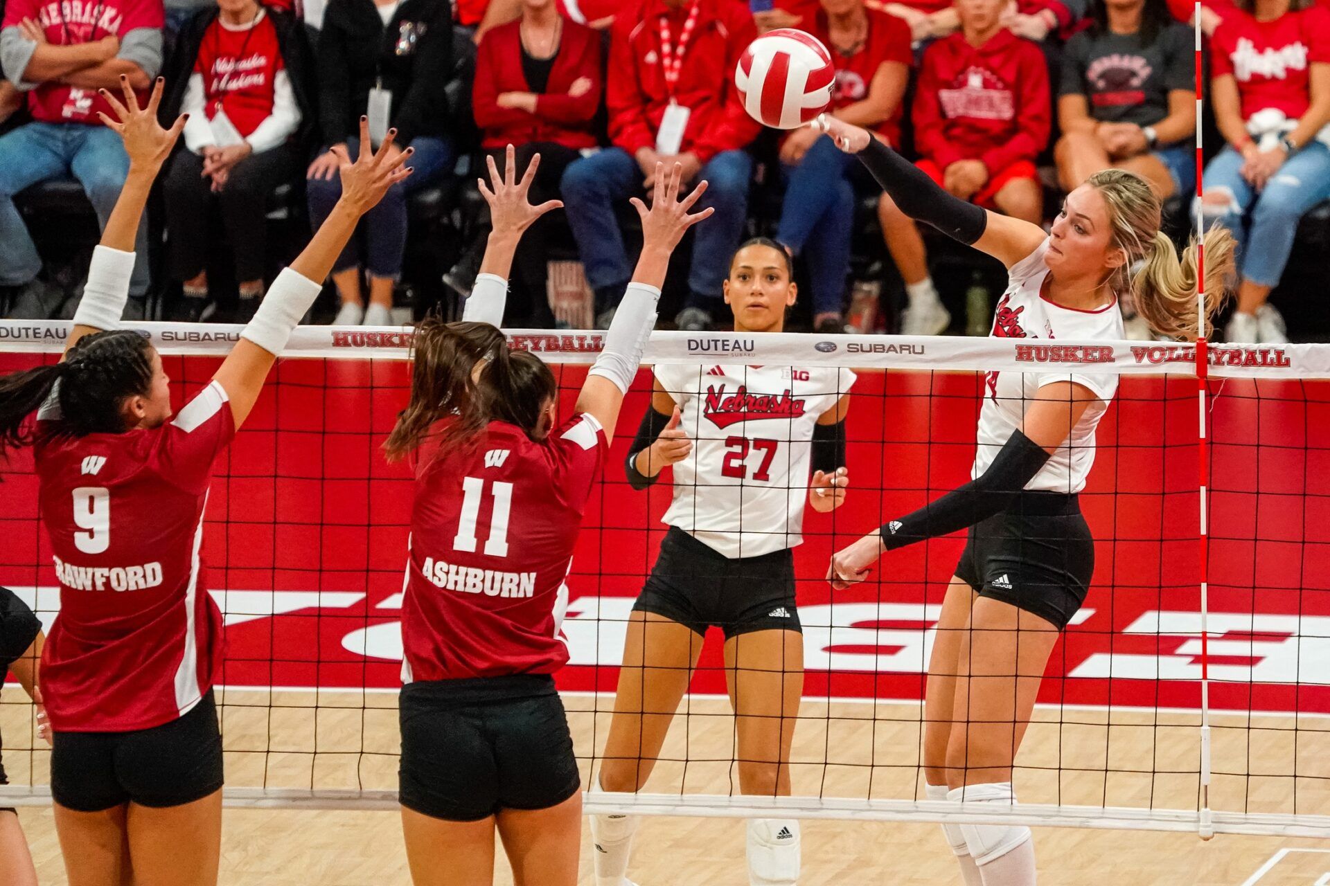 Nebraska Cornhuskers outside hitter Ally Batenhorst (14) attacks against Wisconsin Badgers middle blocker Caroline Crawford (9) and setter Izzy Ashburn (11) during the first set.