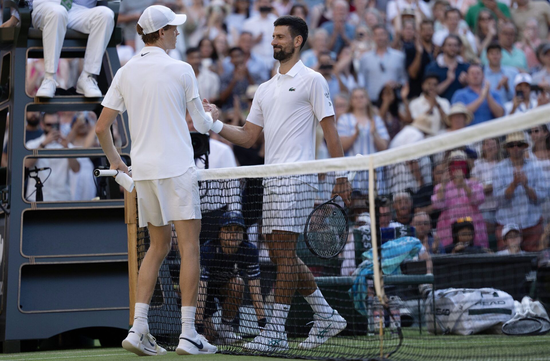 Jannik Sinner of Italy at the net with Novak Djokovic of Serbia after their match on day 12 at All England Lawn Tennis and Croquet Club.