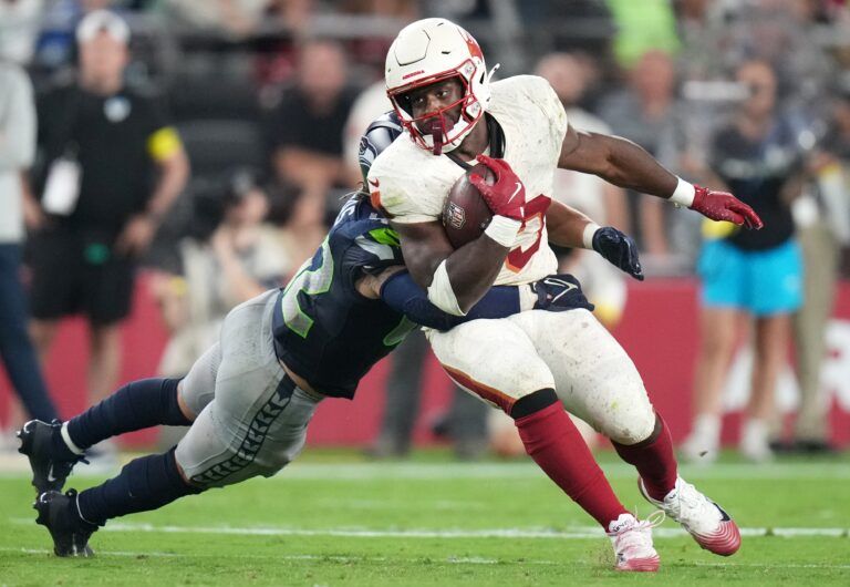 Arizona Cardinals running back Trey Benson (33) tries to break away from Seattle Seahawks linebacker Drake Thomas (42) at State Farm Stadium in Glendale on Sept. 25, 2025.