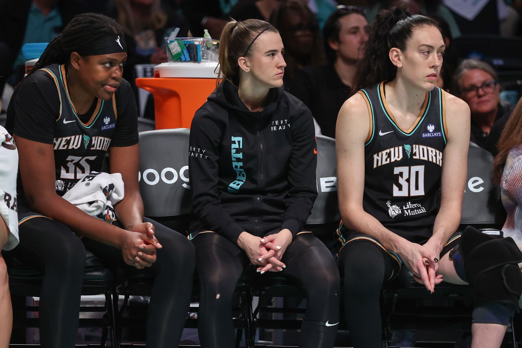 New York Liberty center Jonquel Jones (35), guard Sabrina Ionescu (20), and  forward Breanna Stewart (30) watch from the bench against the Phoenix Mercury during game two of round one for the 2025 WNBA Playoffs at Barclays Center.