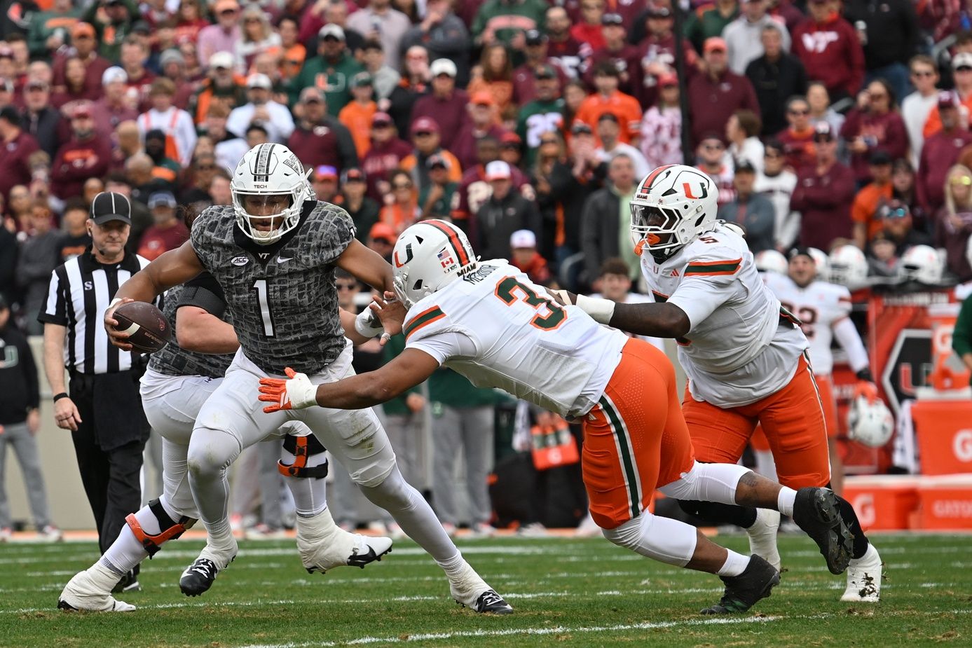 Virginia Tech Hokies quarterback Kyron Drones (1) breaks a tackle from Miami (FL) Hurricanes defensive lineman Akheem Mesidor (3) during the first quarter at Lane Stadium.