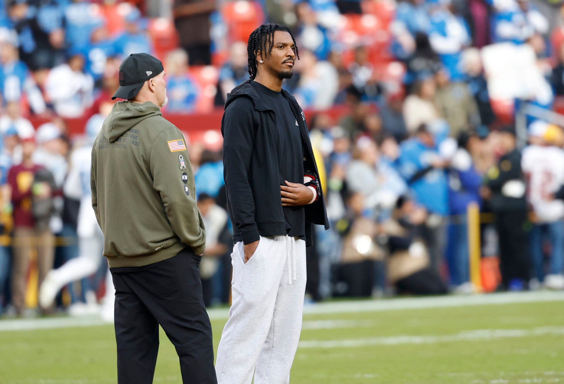Washington Commanders head coach Dan Quinn stands with quarterback Jayden Daniels (5) on the sidelines during warmups prior to a game against the Detroit Lions at Northwest Stadium.