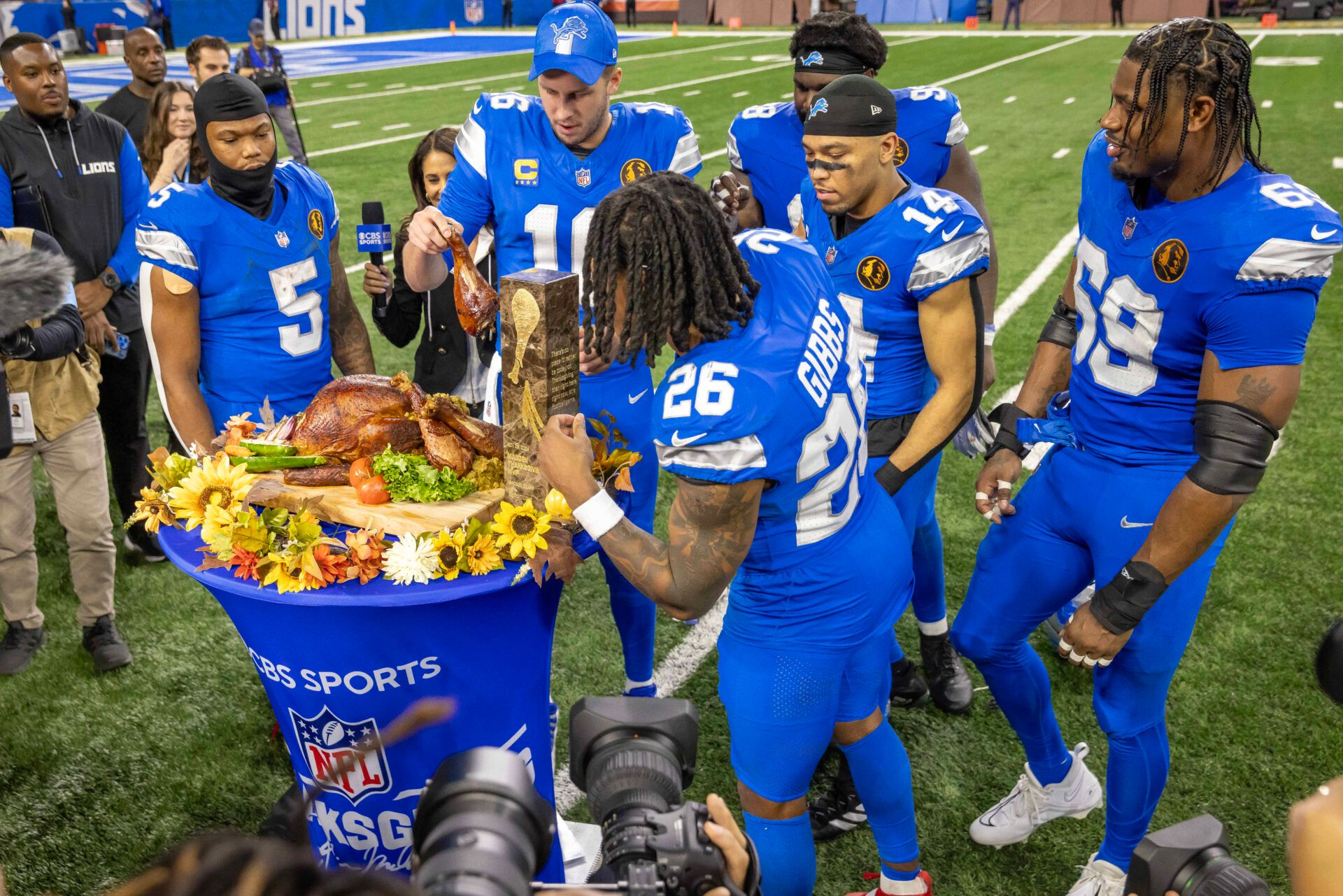 Detroit Lions quarterback Jared Goff (16) passes out pieces of the John Madden MVP Turkey to teammates after the annual Thanksgiving Day game defeating the Chicago Bears at Ford Field.