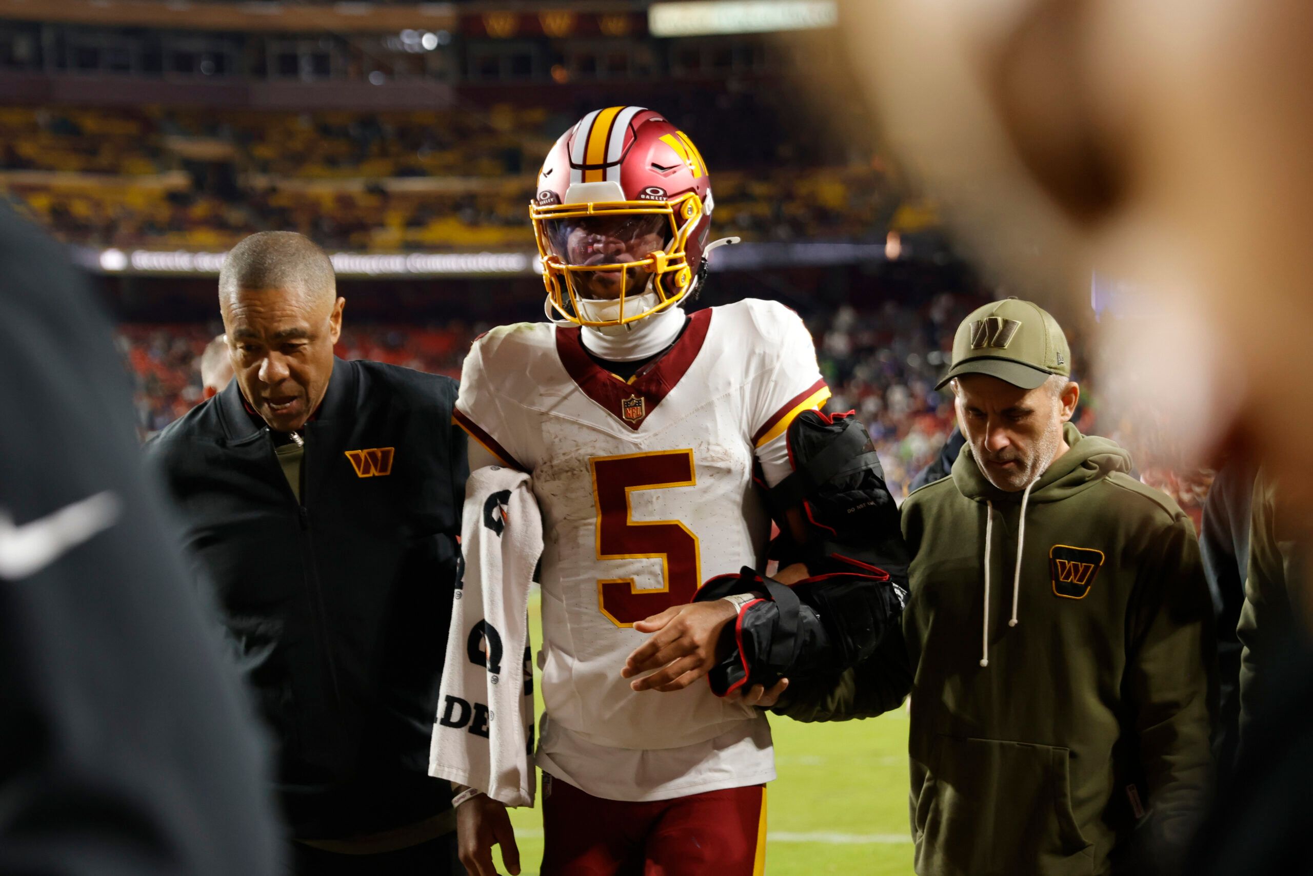 Washington Commanders quarterback Jayden Daniels (5) is helped off the field after an injury during the second half against the Seattle Seahawks at Northwest Stadium.