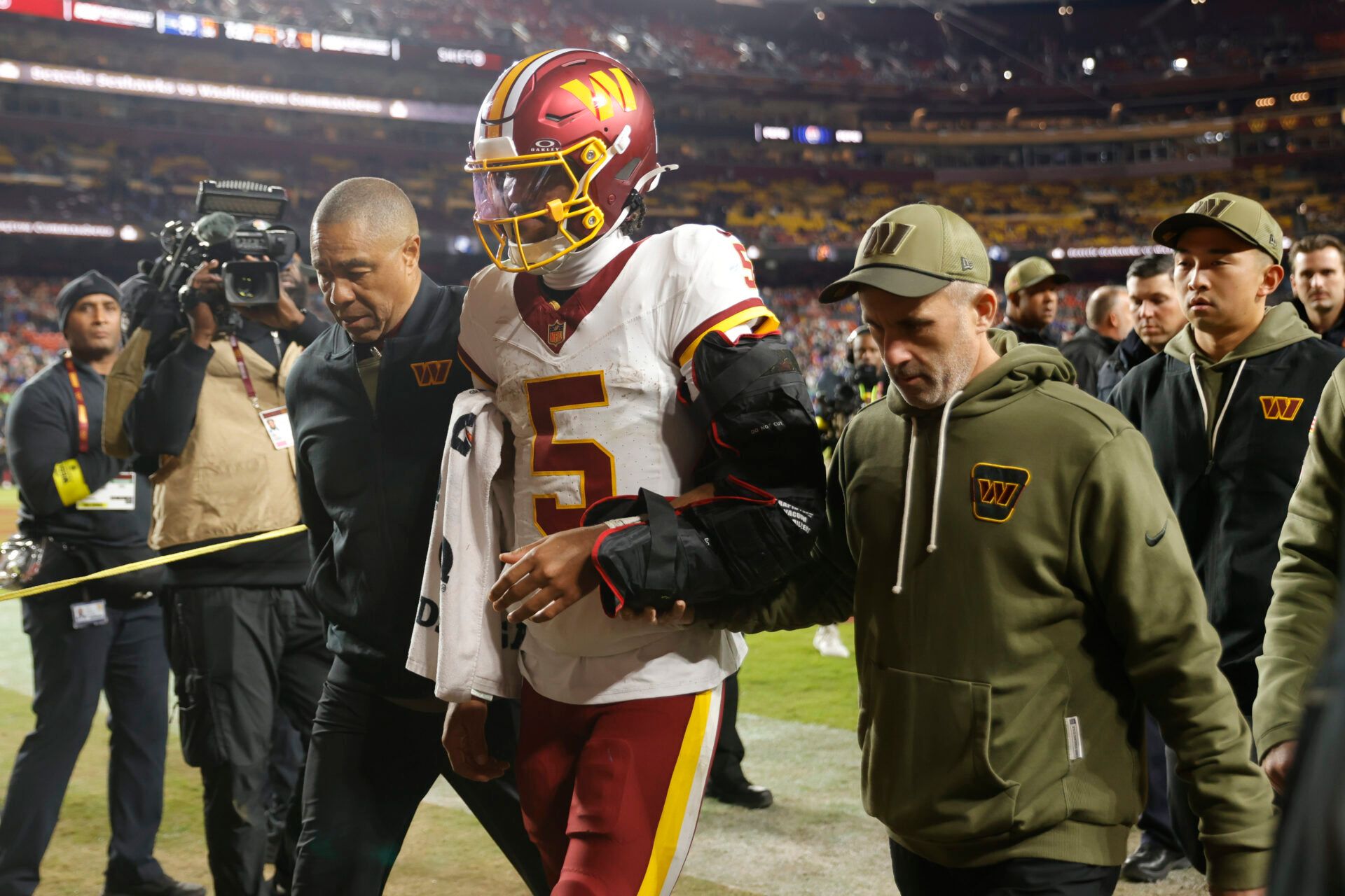 Washington Commanders quarterback Jayden Daniels (5) is helped off the field after an injury during the second half against the Seattle Seahawks at Northwest Stadium.