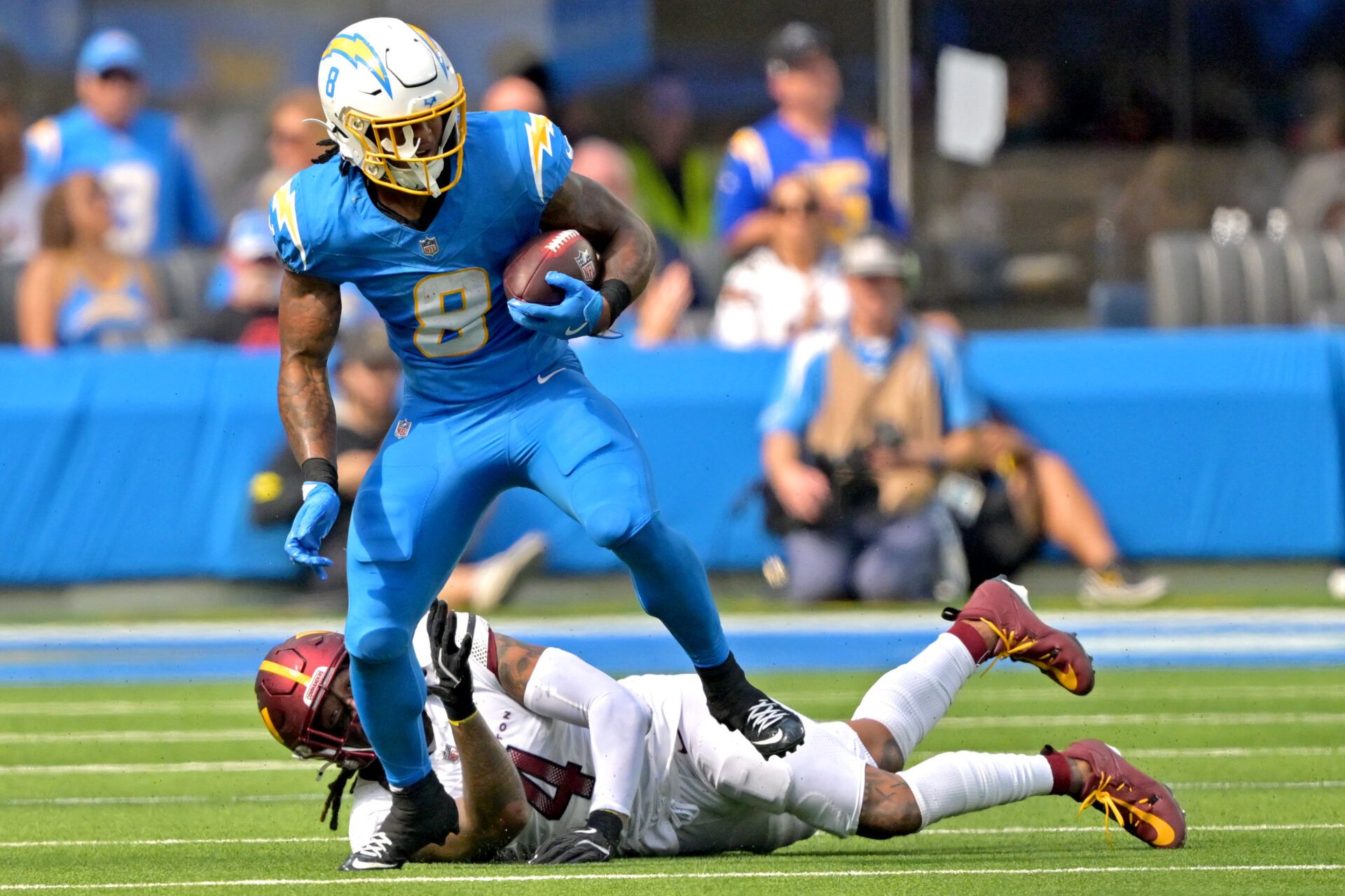 Los Angeles Chargers running back Omarion Hampton (8) breaks away from Washington Commanders linebacker Frankie Luvu (4) as he carries the ball at SoFi Stadium.