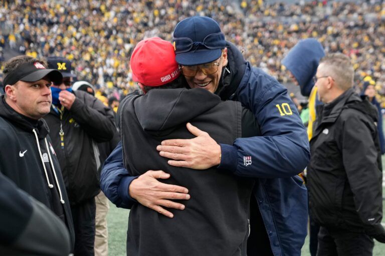 Ohio State Buckeyes defensive coordinator Matt Patricia hugs Tom Brady prior to the NCAA football game against the Michigan Wolverines at Michigan Stadium in Ann Arbor, Mich. on Nov. 29, 2025.