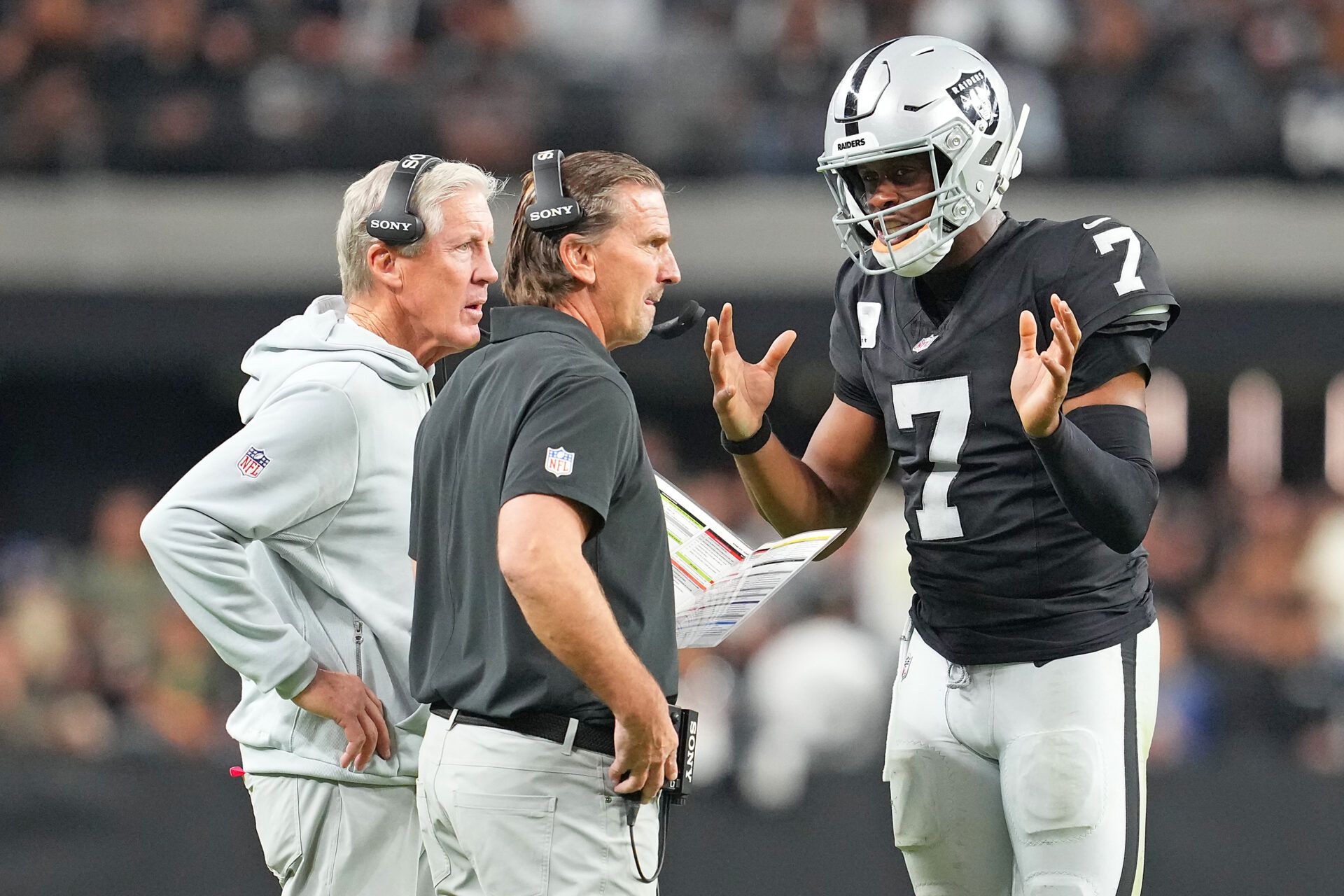 Las Vegas Raiders quarterback Geno Smith (7) talks with head coach Pete Carroll and quarterbacks coach Greg Olsen in a game against the Cleveland Browns during the fourth quarter at Allegiant Stadium.