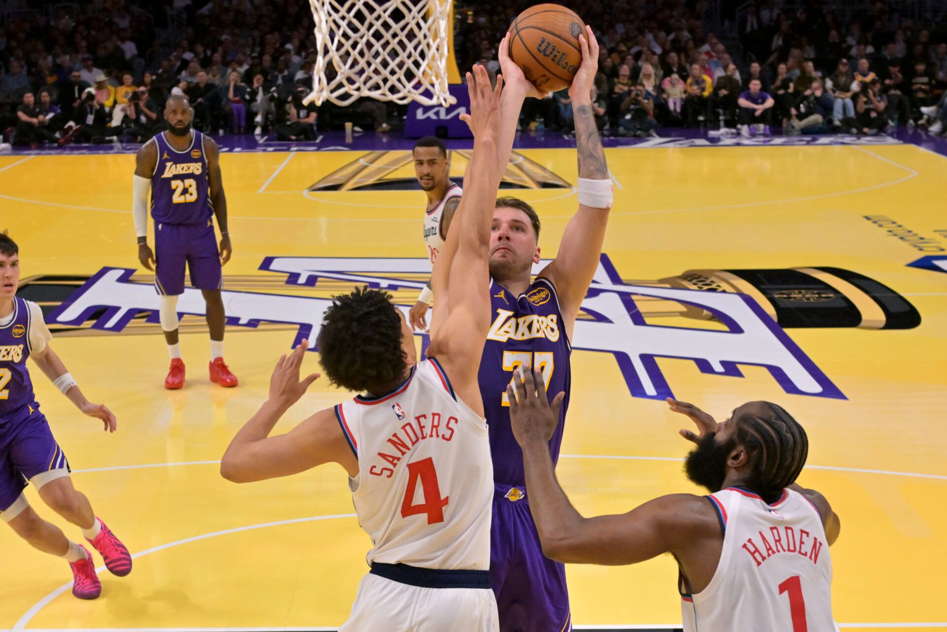 Los Angeles Clippers guard Kobe Sanders (4) and guard James Harden (1) defend a shot by Los Angeles Lakers guard Luka Doncic (77) in the second half at Crypto.com Arena.