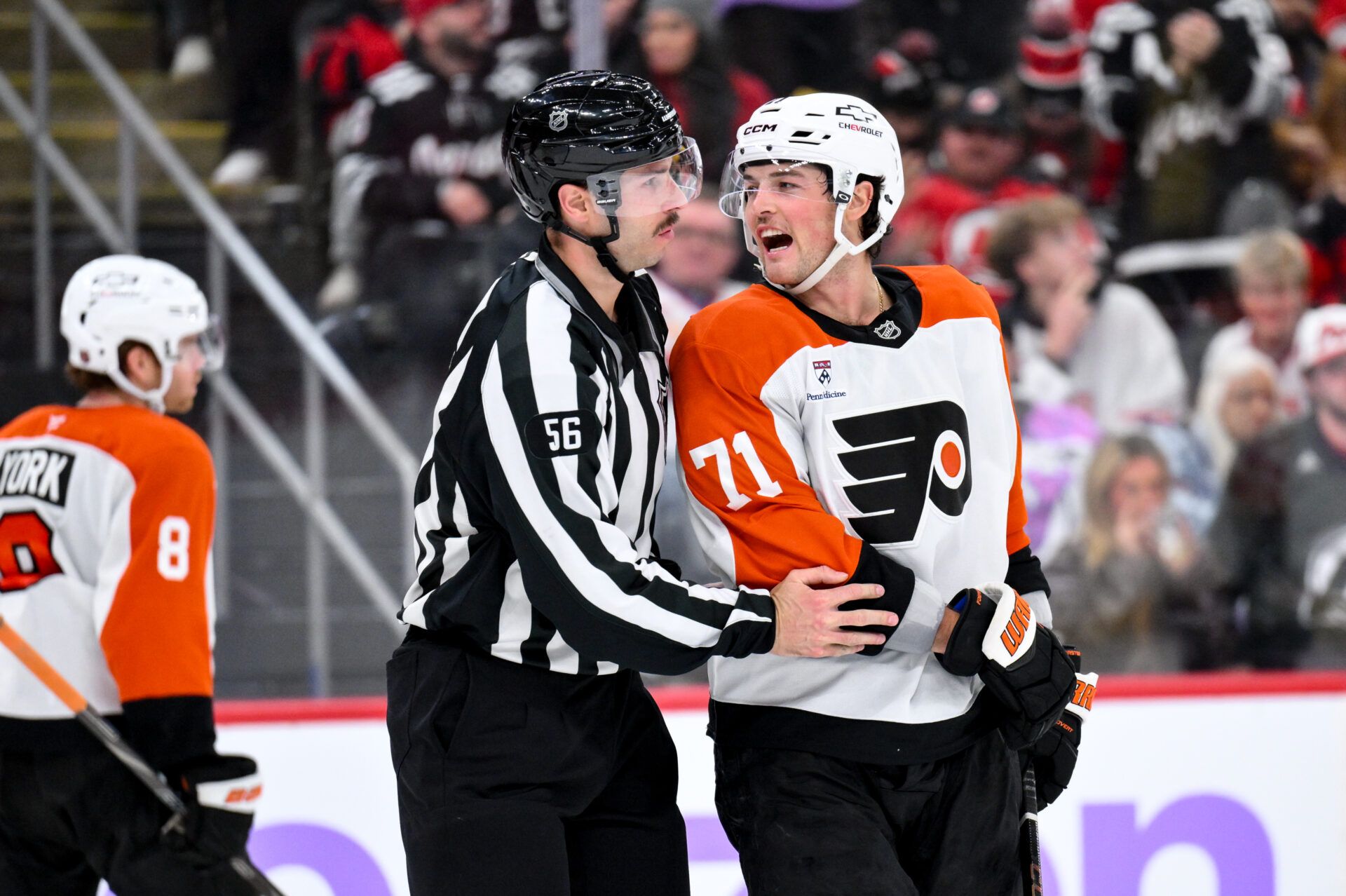Philadelphia Flyers right wing Tyson Foerster (71) is restrained by linesman Julien Fournier (56) during the third period against the New Jersey Devils at Prudential Center.