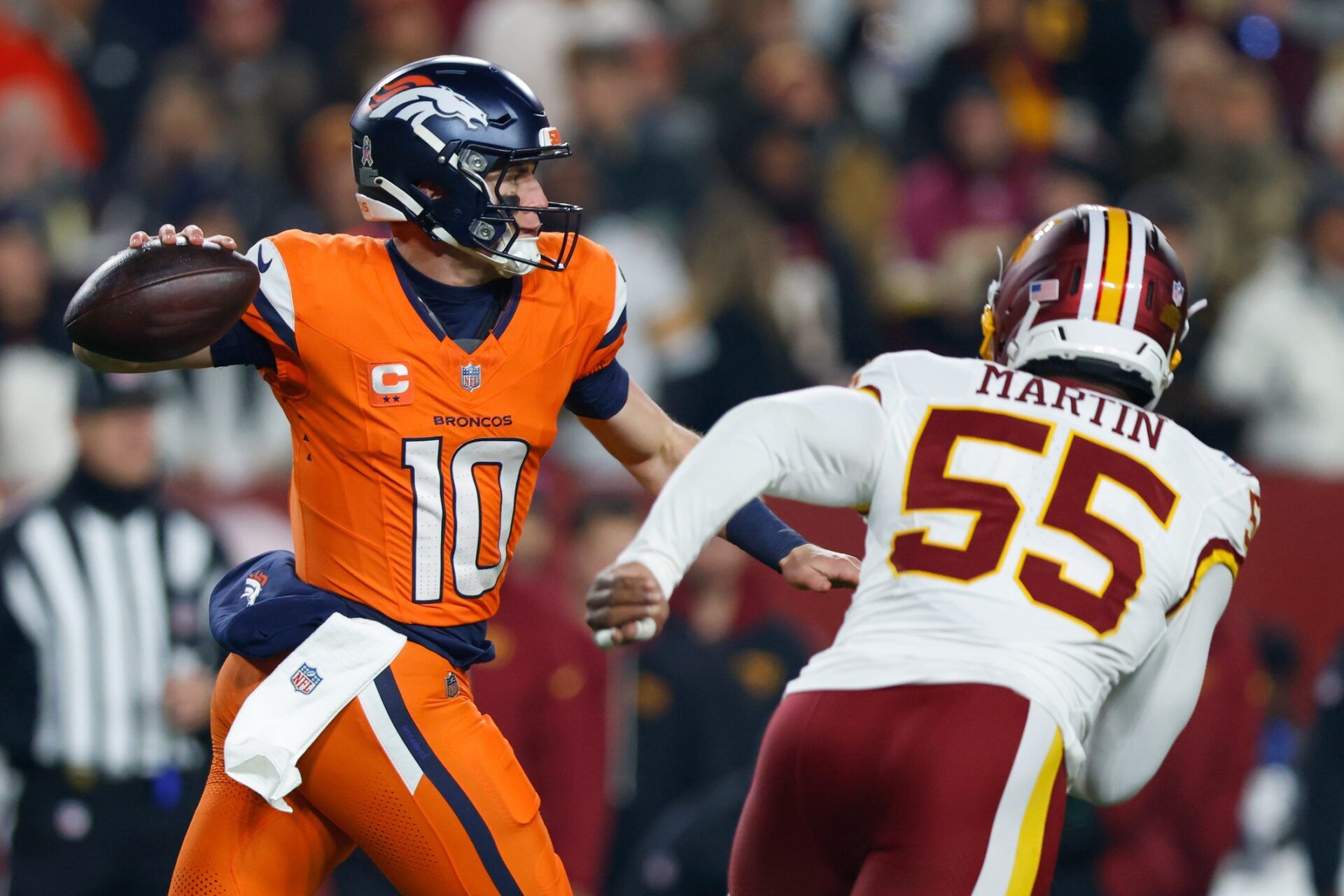 Denver Broncos quarterback Bo Nix (10) passes the ball under pressure from Washington Commanders defensive end Jacob Martin (55) in the first quarter of the game at Northwest Stadium.