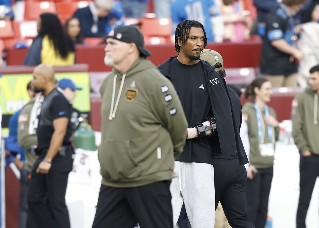 Washington Commanders head coach Dan Quinn stands with quarterback Jayden Daniels (5) on the sidelines during warmups prior to a game against the Detroit Lions at Northwest Stadium.