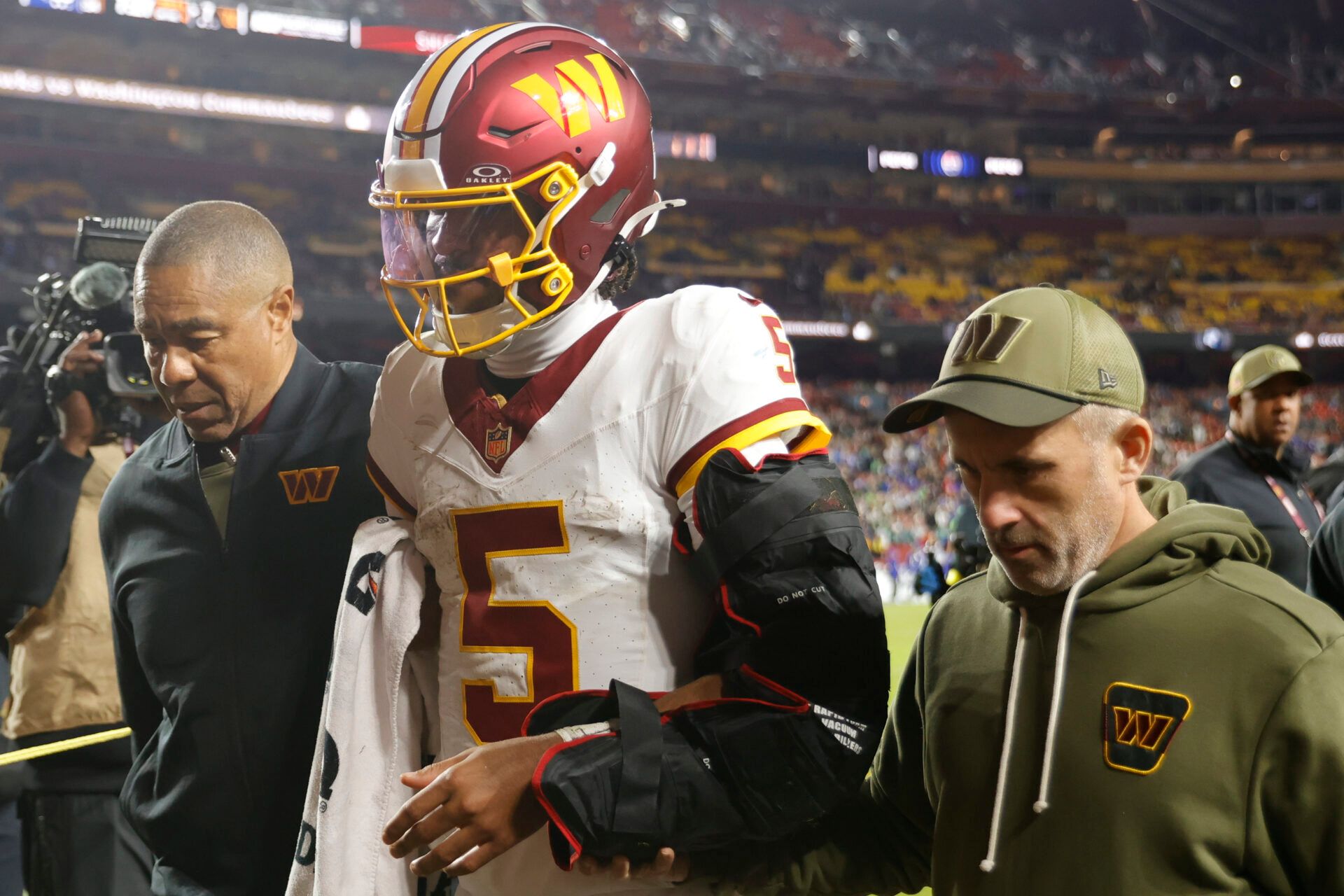 Washington Commanders quarterback Jayden Daniels (5) is helped off the field after an injury during the second half against the Seattle Seahawks at Northwest Stadium.