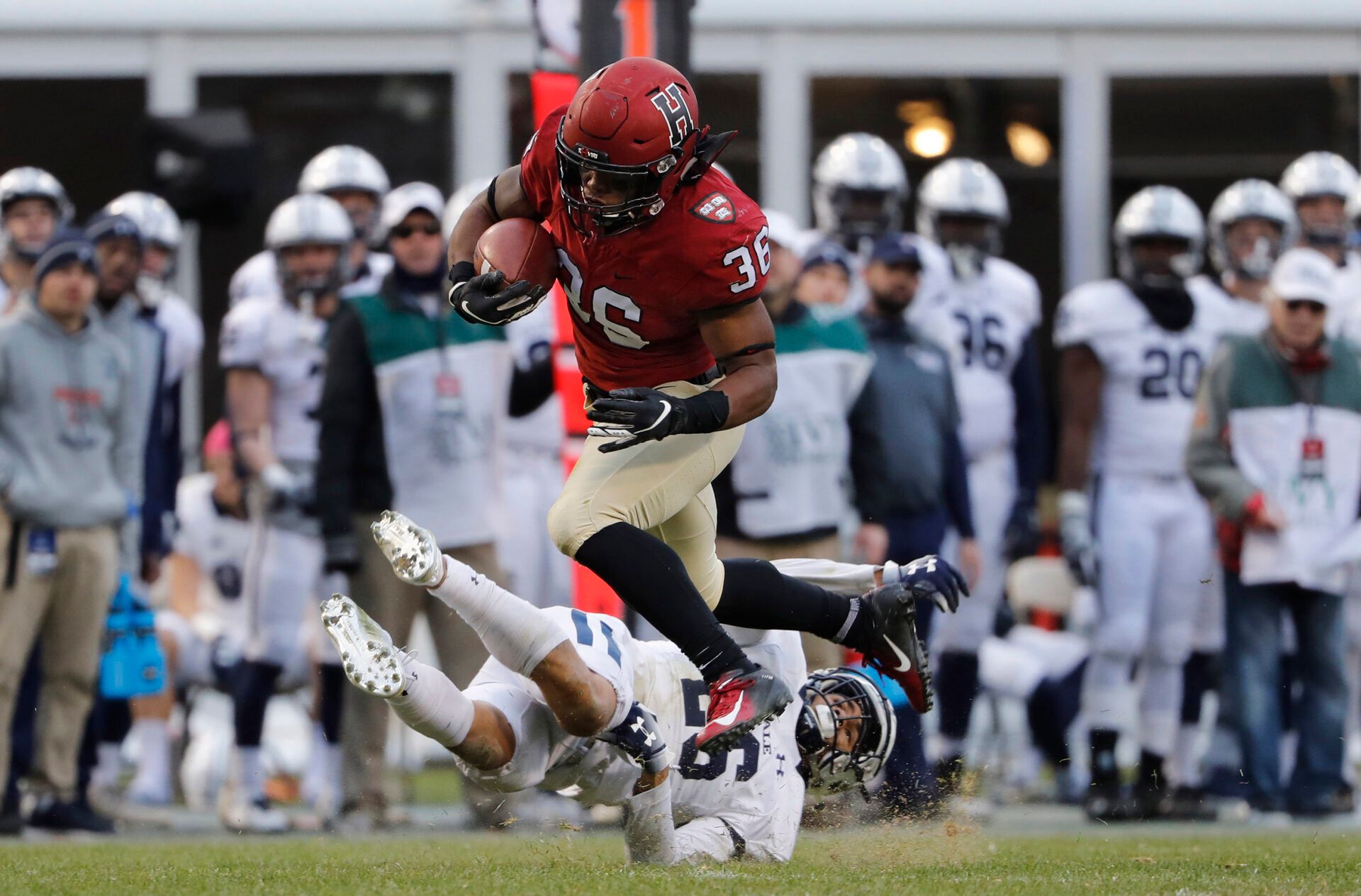 Harvard running back Devin Darrington (36) runs over Yale defensive back Rodney Thomas II (26) during the second half at Fenway Park.