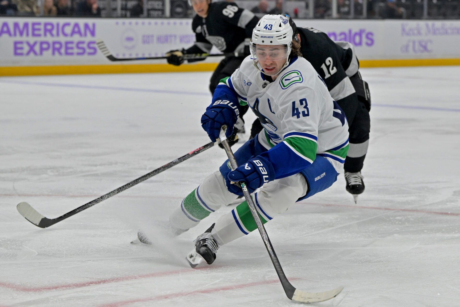 Vancouver Canucks defenseman Quinn Hughes (43) is pressured by Los Angeles Kings left wing Trevor Moore (12) during the second period at Crypto.com Arena.