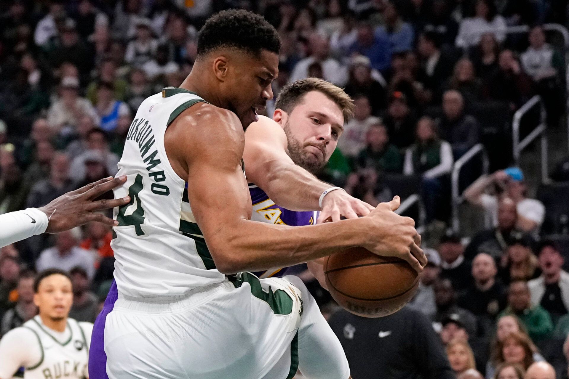 Milwaukee Bucks forward Giannis Antetokounmpo (34) and Los Angeles Lakers guard Luka Doncic (77) battle for control of the ball during the first quarter at Fiserv Forum.
