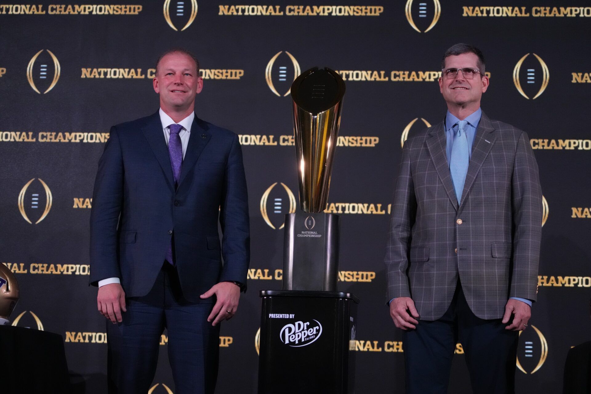 Washington Huskies coach Kalen DeBoer (left) and Michigan Wolverines coach Jim Harbaugh pose with the College Football Playoff national championship trophy at the CFP National Championship Head Coaches press conference at JW Marriot Houston by the Galleria.