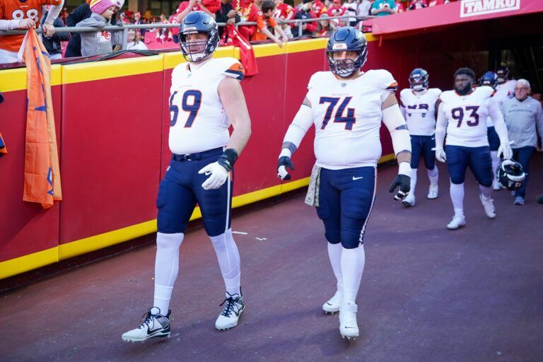 Denver Broncos offensive tackle Mike McGlinchey (69) and guard Ben Powers (74) enter the field against the Kansas City Chiefs for warm ups prior to a game at GEHA Field at Arrowhead Stadium.