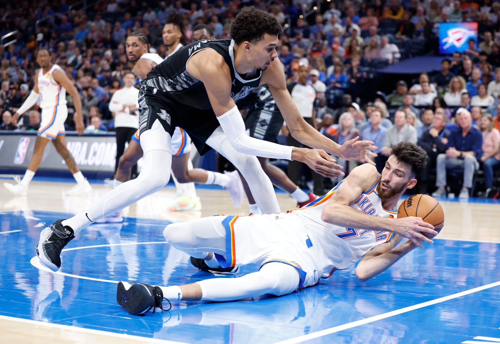 San Antonio Spurs center Victor Wembanyama (1) works to steal the ball from Oklahoma City Thunder forward Chet Holmgren (7) after he fell to the floor during the second half at Paycom Center.
