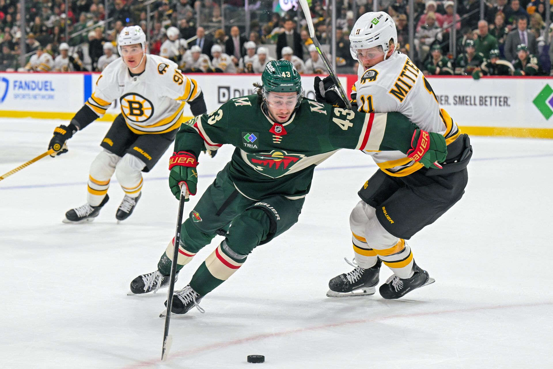 Minnesota Wild defensemen Quinn Hughes (43) protects the puck from Boston Bruins forward Casey Mittelstadt (11) during the second period at Grand Casino Arena.