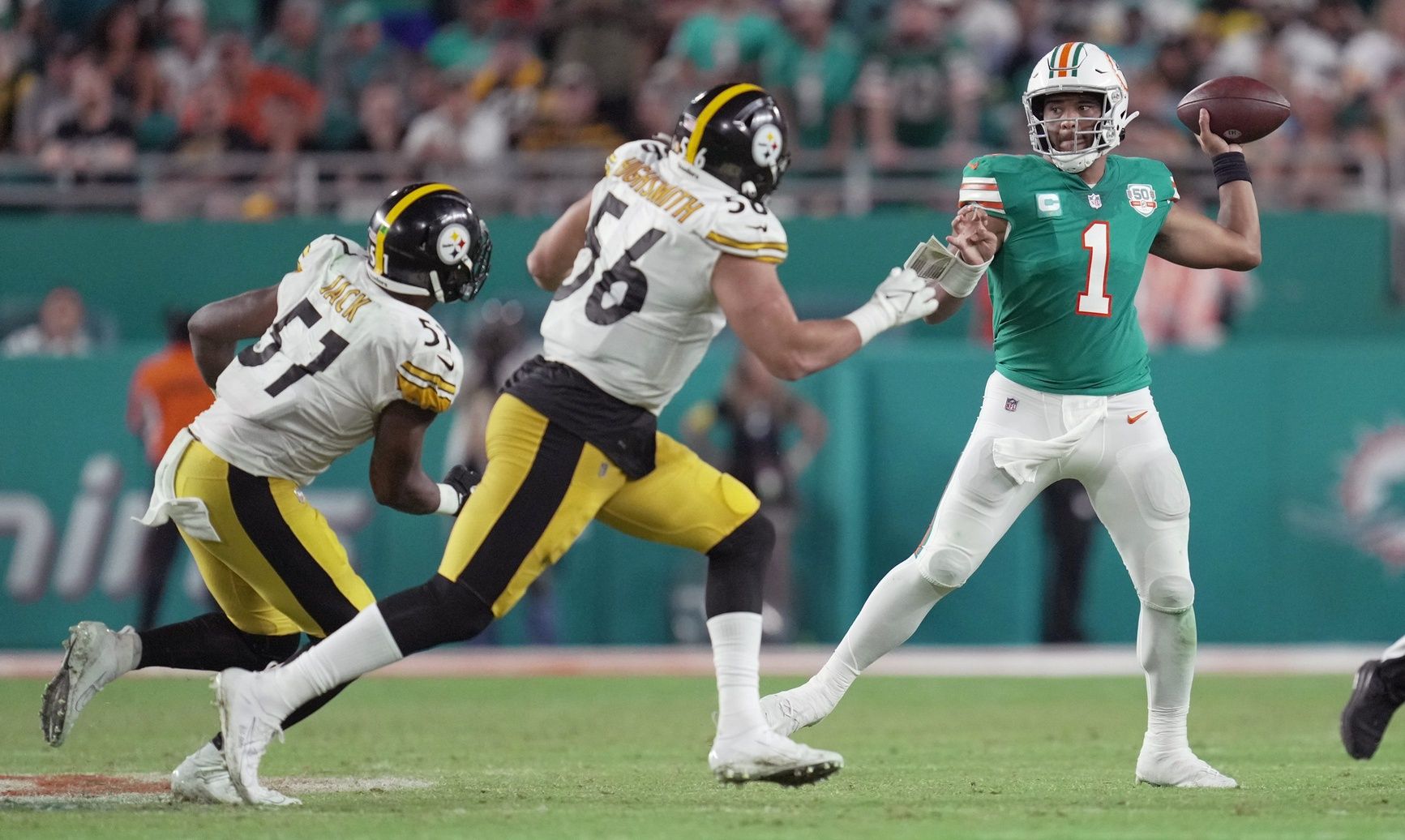 Miami Dolphins quarterback Tua Tagovailoa (1) drops back to pass in the fourth quarter as Pittsburgh Steelers linebacker Alex Highsmith (56) and defensive tackle Montravius Adams (57) close in on the play at Hard Rock Stadium in Miami Gardens, Oct. 23, 2022.