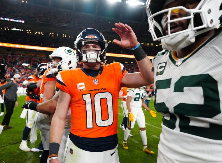 Denver Broncos quarterback Bo Nix (10) high-fives Green Bay Packers defensive end Rashan Gary (52) following a win over the Green Bay Packers at Empower Field at Mile High.