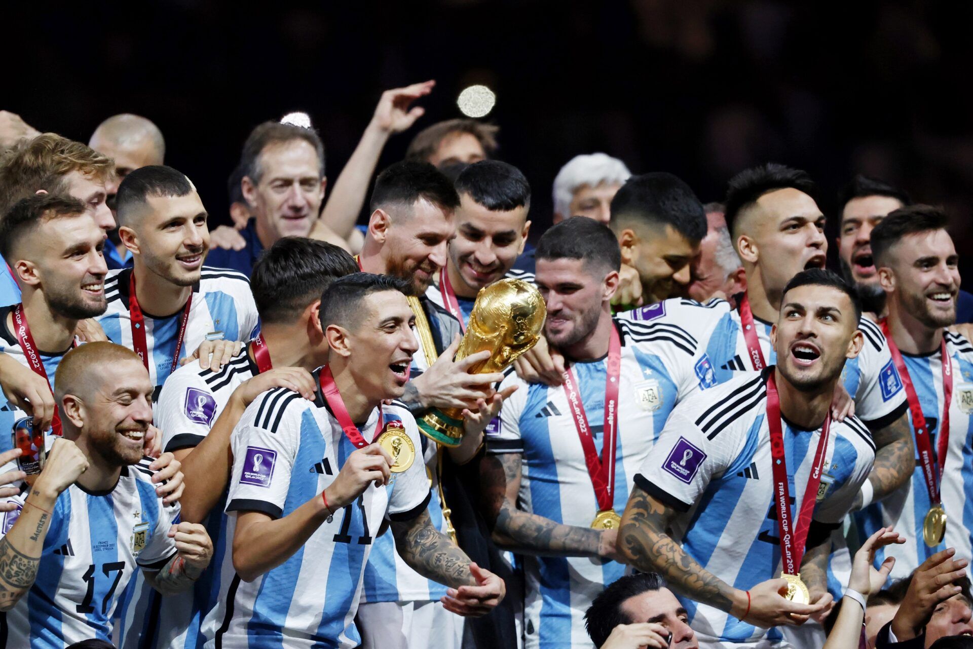 Argentina forward Lionel Messi (10) holds the World Cup trophy as he and his teammates celebrate after winning the 2022 World Cup final against France at Lusail Stadium.