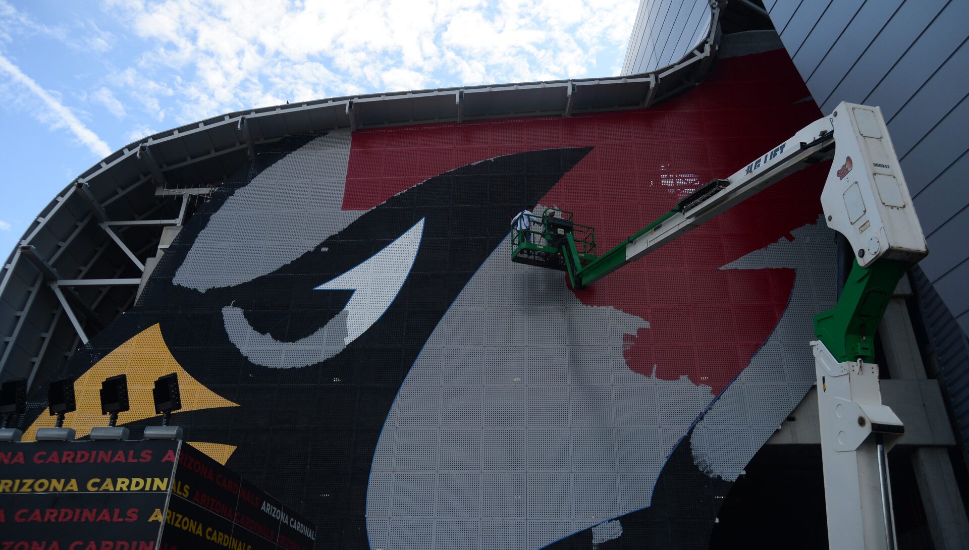 A painter works on the details of the Arizona Cardinals logo on State Farm Stadium during training camp.