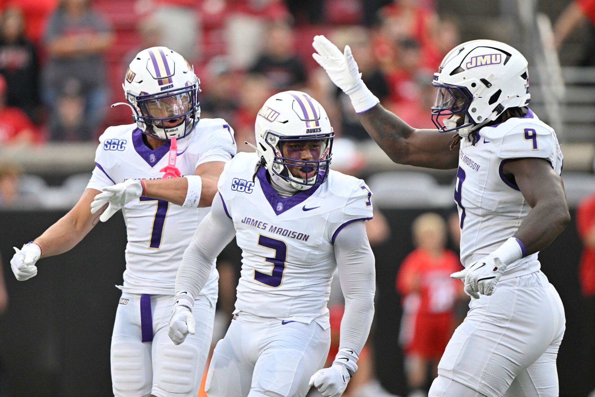 James Madison Dukes linebacker Gannon Weathersby (3) celebrates with safety Jacob Thomas (7) and defensive lineman Xavier Holmes (9) during the first half against the Louisville Cardinals at L&N Federal Credit Union Stadium.