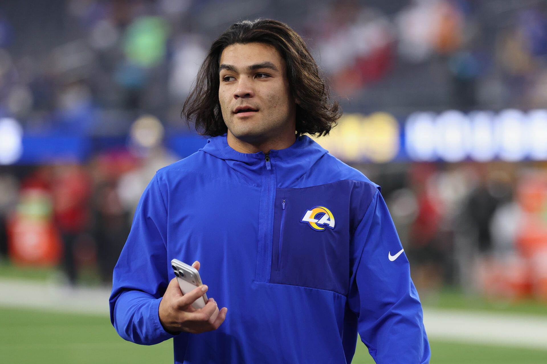 Los Angeles Rams wide receiver Puka Nacua (12) walks on the field holding a mobile phone during warmups before the game against the Tampa Bay Buccaneers at SoFi Stadium.