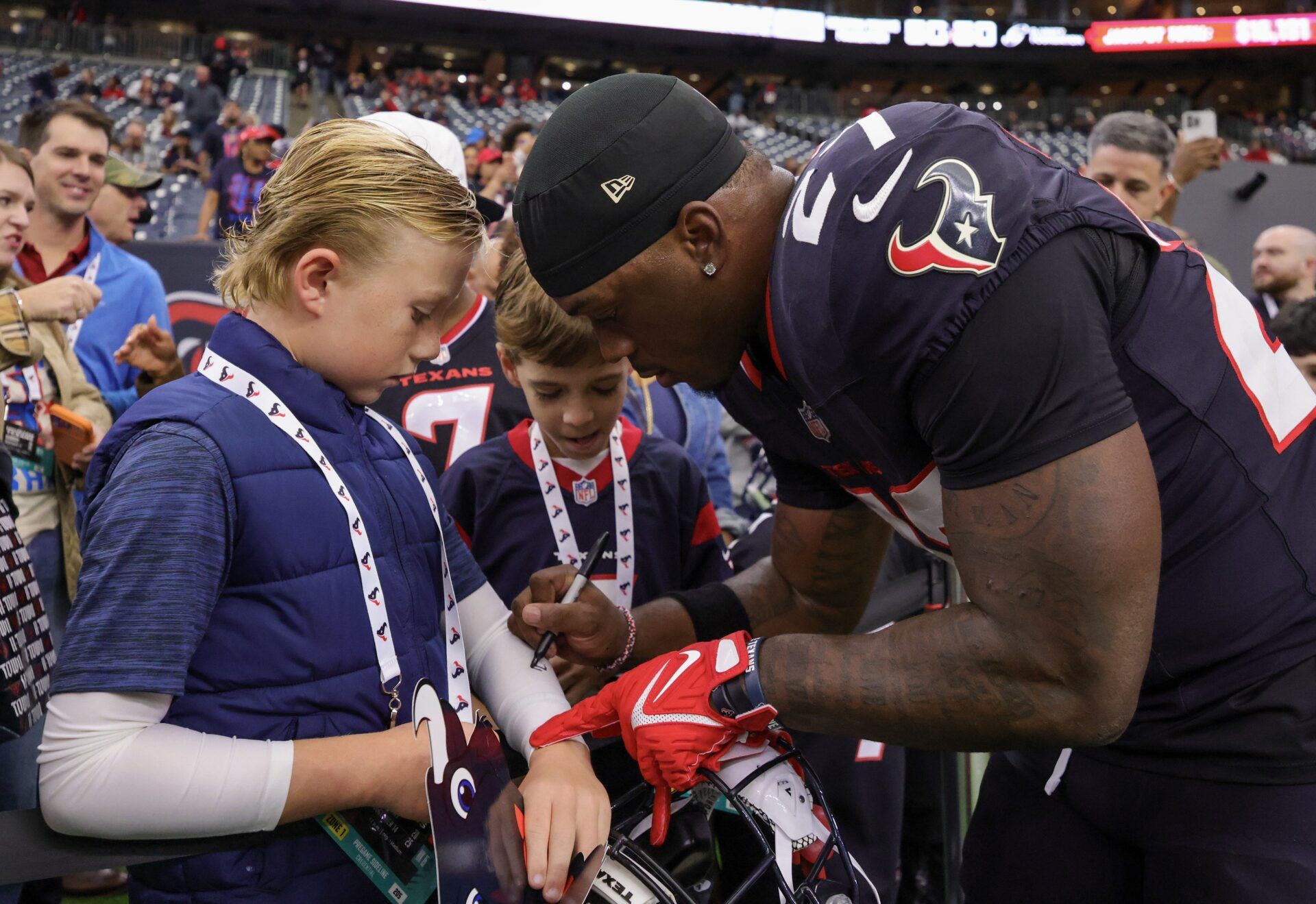 Houston Texans running back Woody Marks (27) signs an autograph for a fan before playing against the Arizona Cardinals at NRG Stadium.