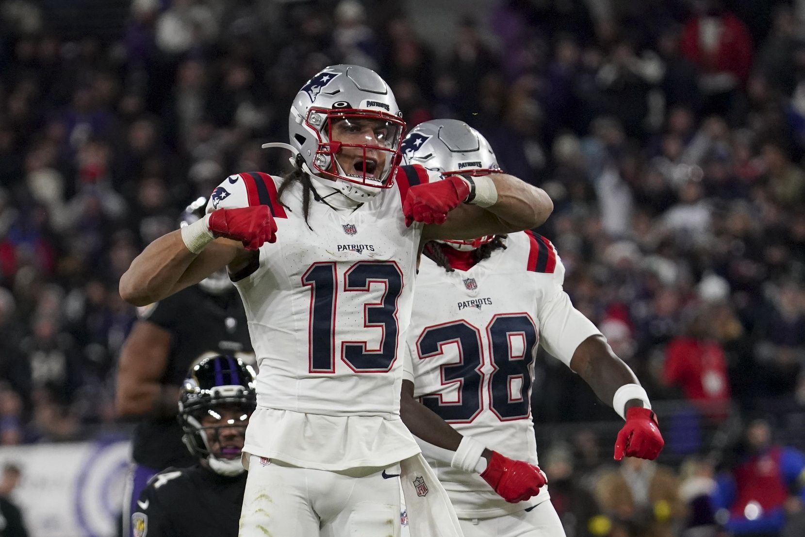 New England Patriots wide receiver Mack Hollins (13) celebrates a catch against Baltimore Ravens safety Kyle Hamilton (14) with New England Patriots running back Rhamondre Stevenson (38) during the first half of the game at M&T Bank Stadium.