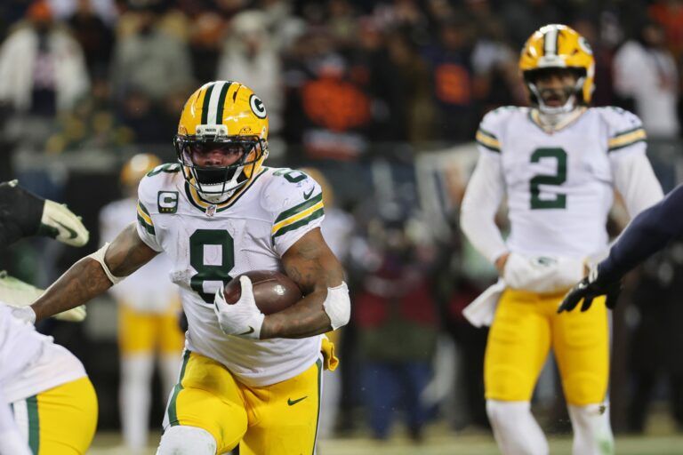 Green Bay Packers running back Josh Jacobs (8) runs the ball and quarterback Malik Willis (2) watches the play against the Chicago Bears during the third quarter at Soldier Field.
