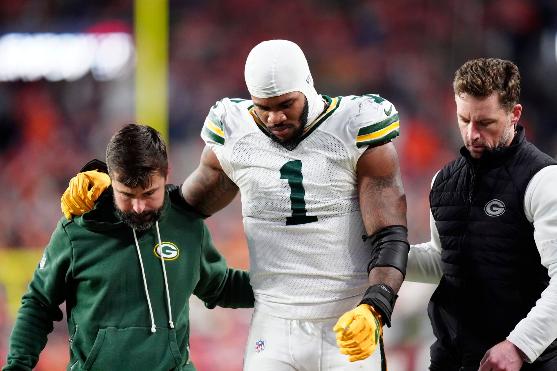 Green Bay Packers defensive end Micah Parsons (1) walks off the field with help from medical personnel following an injury during the third quarter against the Denver Broncos at Empower Field at Mile High.