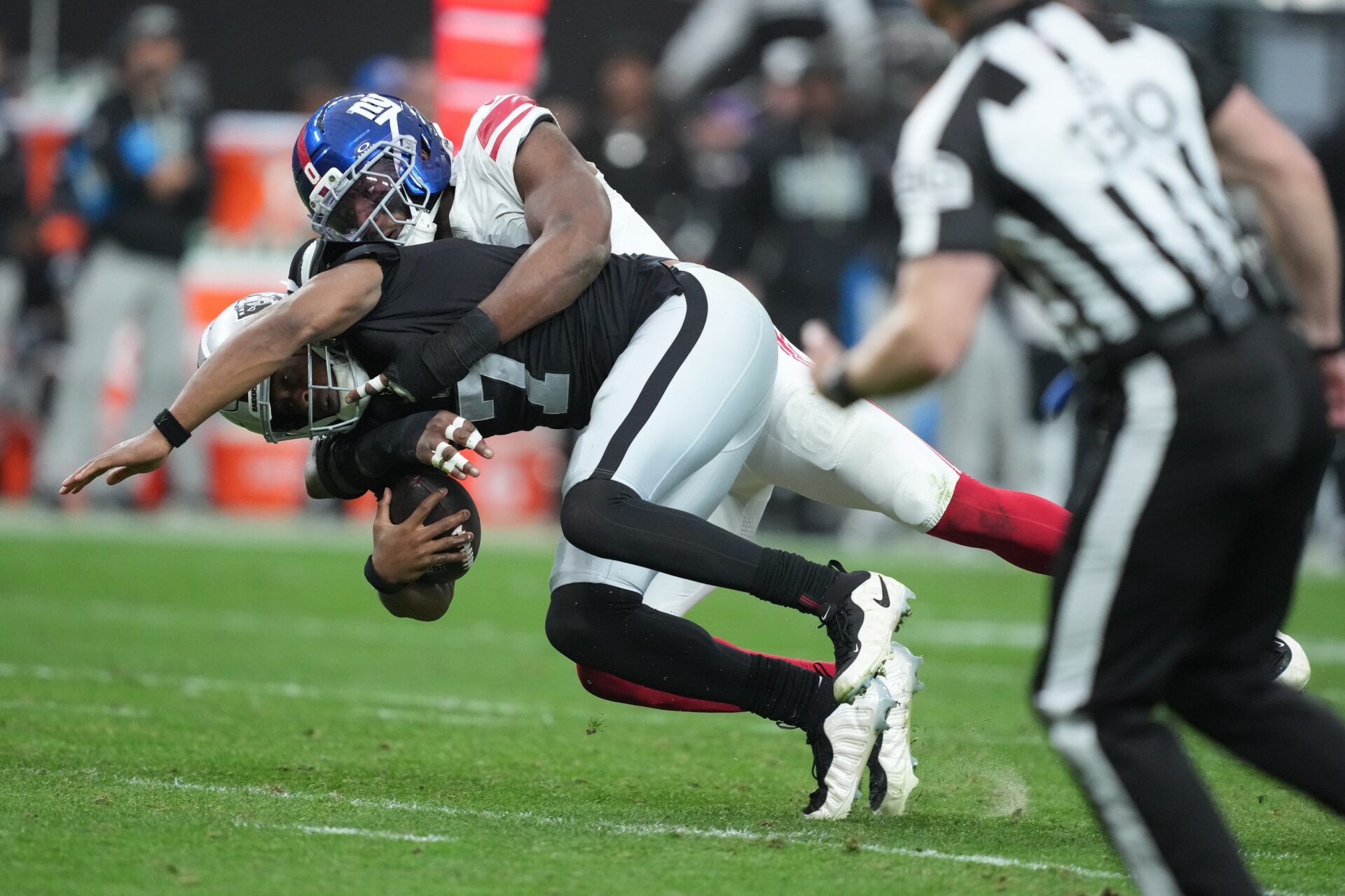 Las Vegas Raiders quarterback Geno Smith (7) is tackled by New York Giants outside linebacker Brian Burns (0) in the second half at Allegiant Stadium.