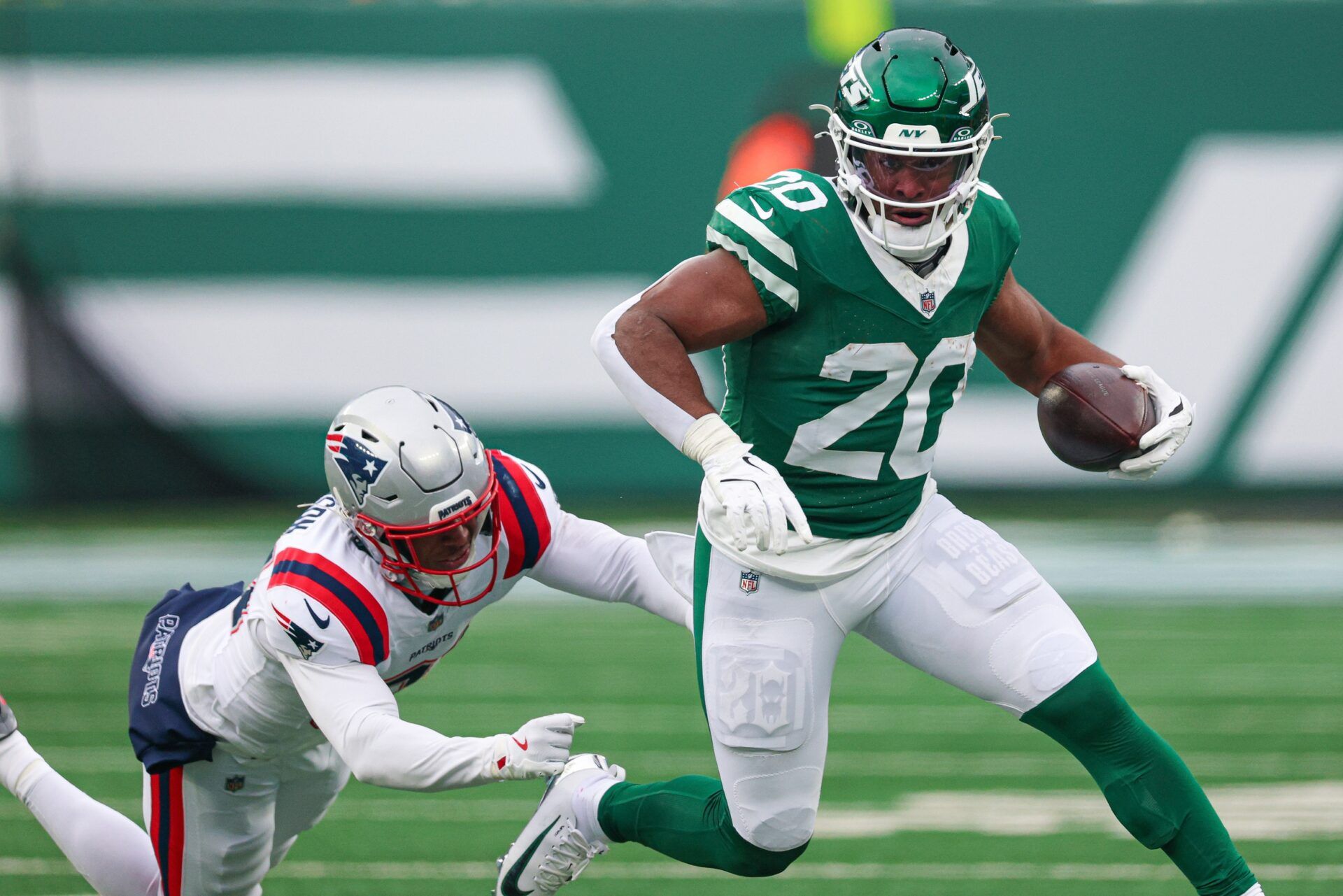 New York Jets running back Breece Hall (20) carries the ball as New England Patriots linebacker K'Lavon Chaisson (44) pursues at MetLife Stadium.