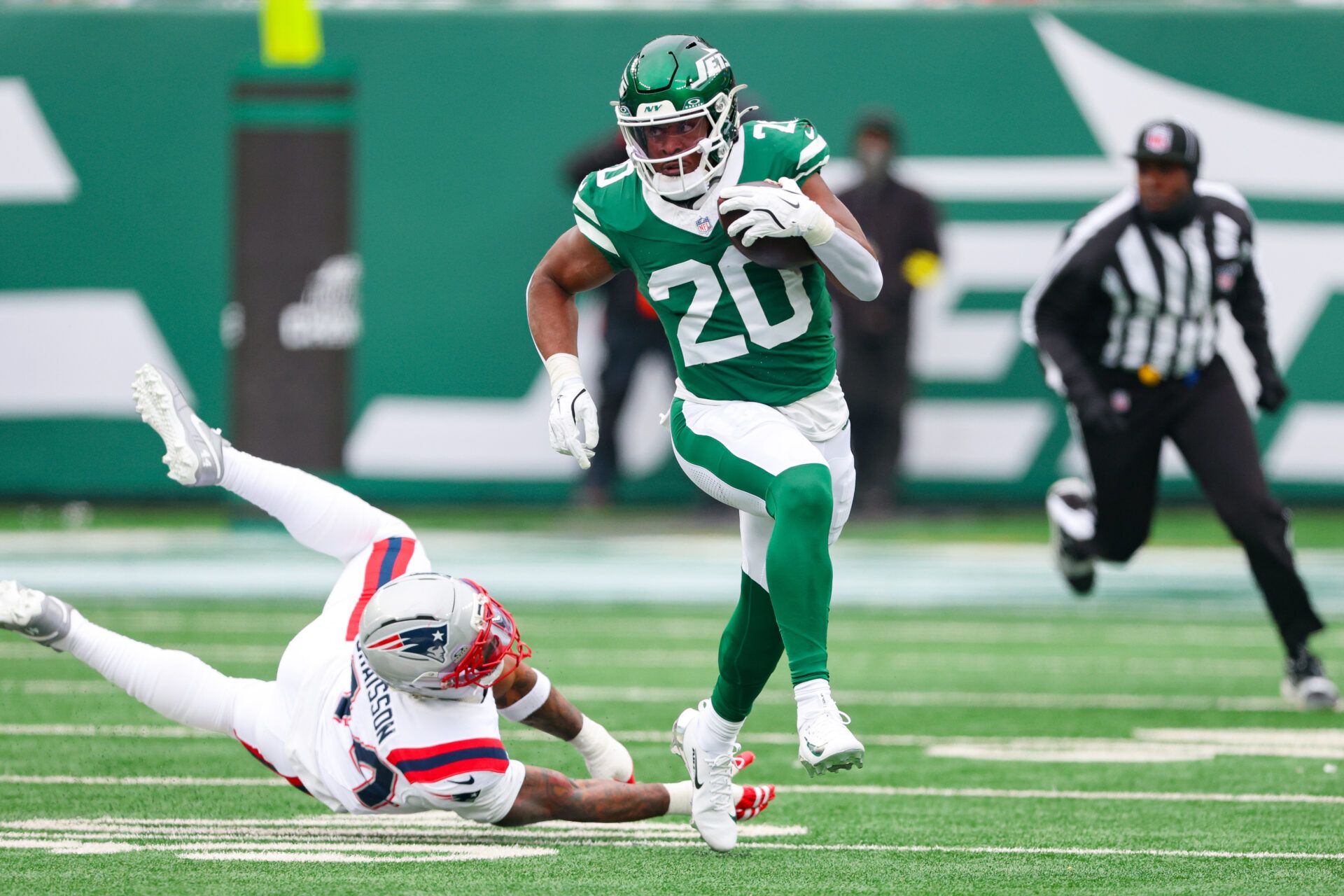 New York Jets running back Breece Hall (20) carries the ball asNew England Patriots linebacker K'Lavon Chaisson (44) pursues during the first half at MetLife Stadium.