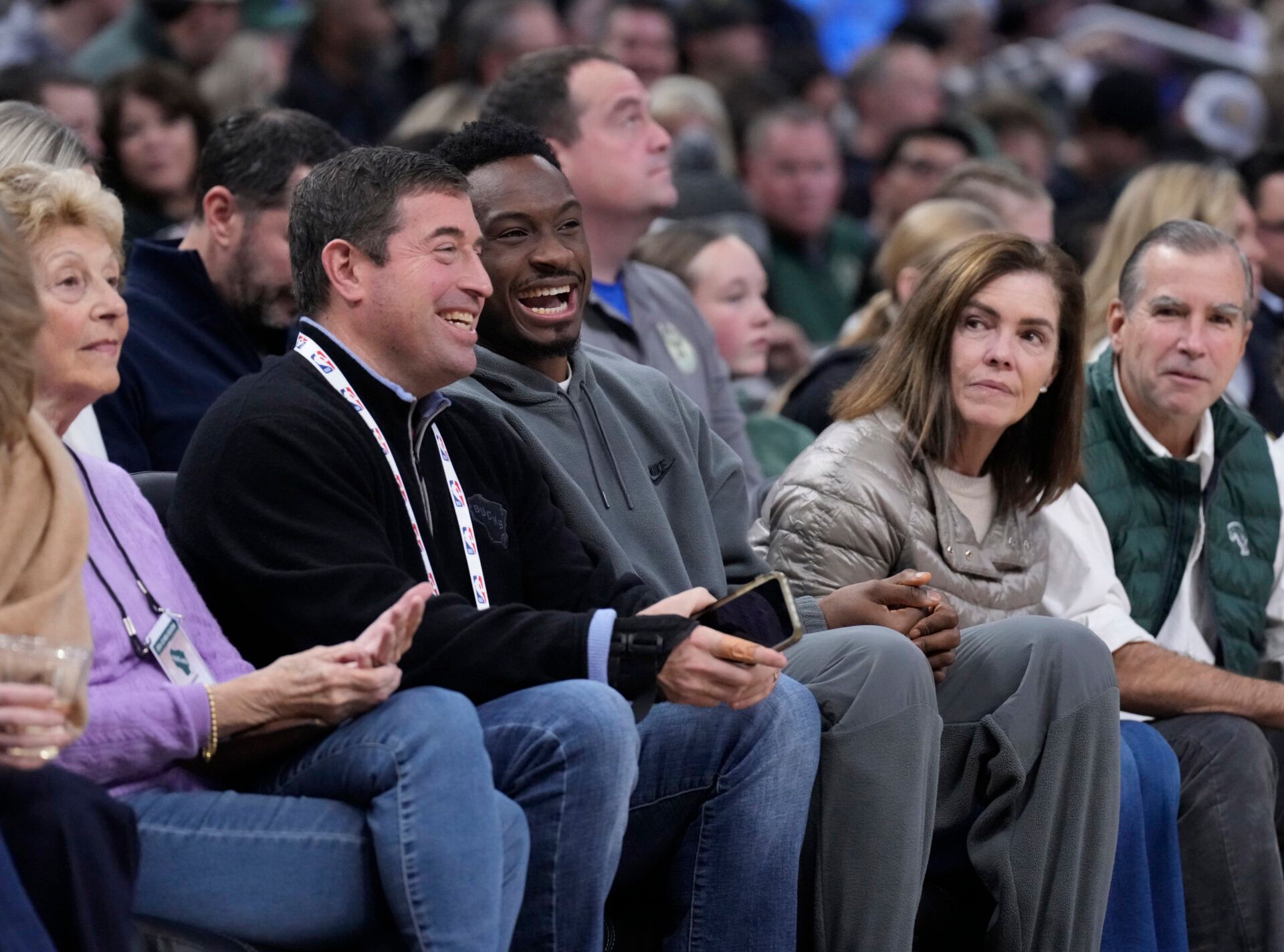 Thanasis Antetokounmpo (34) shares a laugh with Milwaukee Bucks team president Peter Feigin during the Milwaukee Bucks and Charlotte Hornets game at Fiserv Forum.