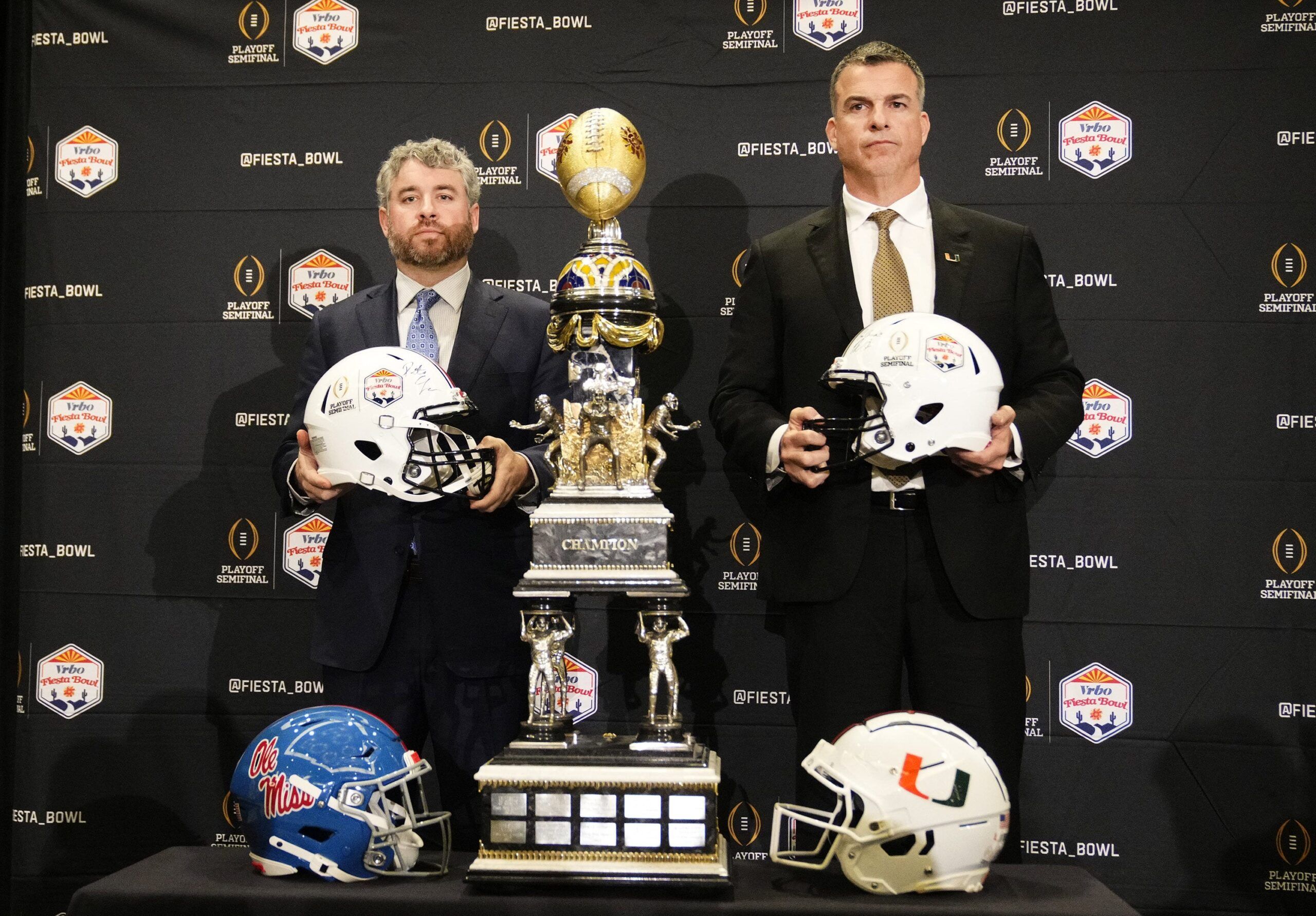 Head coach Pete Golding of Mississippi and head coach Mario Cristobal of Miami (right) pose with the trophy before their matchup at the Fiesta Bowl during a news conference at the JW Marriott Scottsdale Camelback Inn Resort on Jan. 7, 2026.