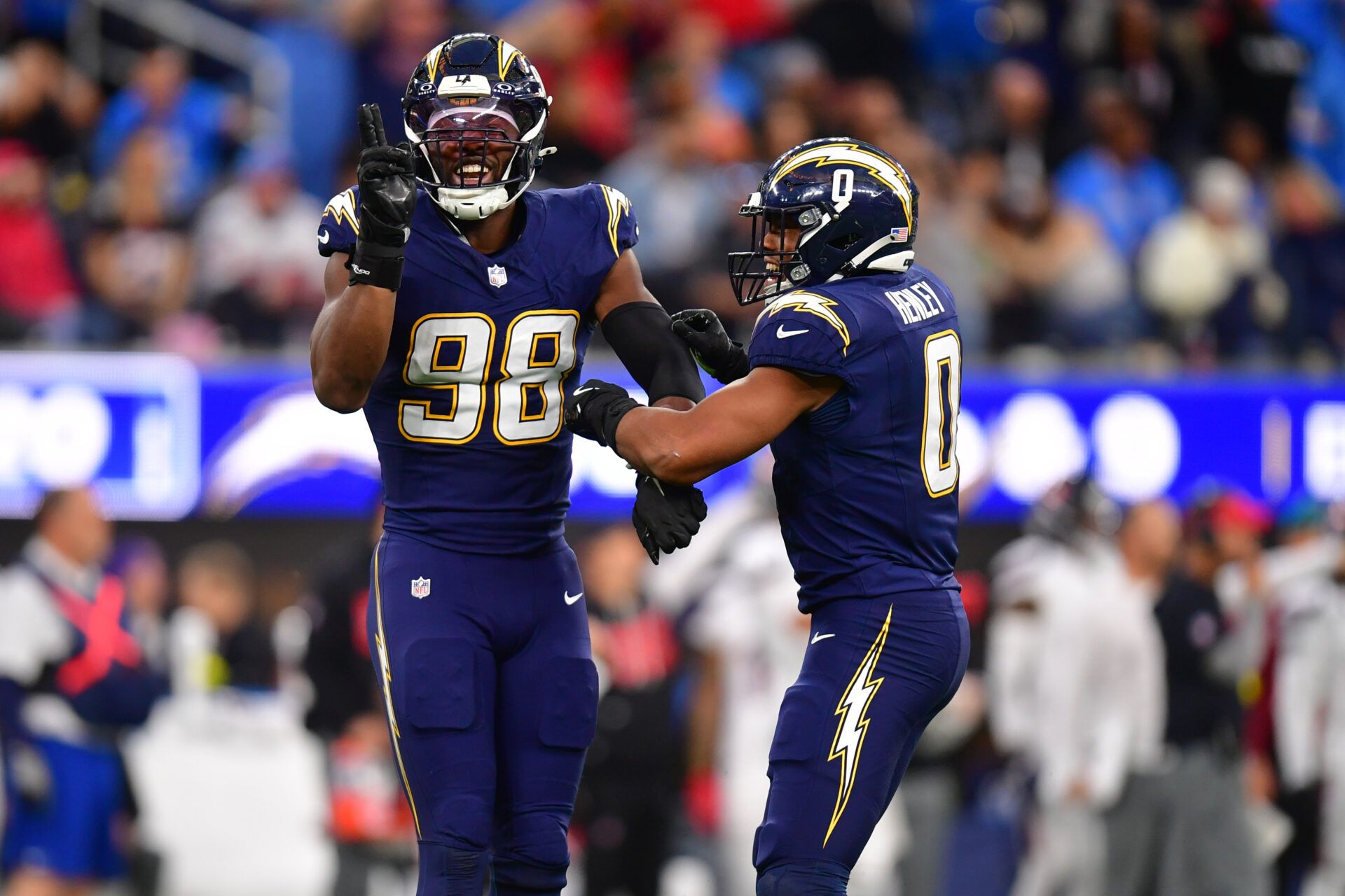 Los Angeles Chargers linebacker Odafe Oweh (98) and linebacker Daiyan Henley (0) react after a defensive play against the Houston Texans during the second half at SoFi Stadium.