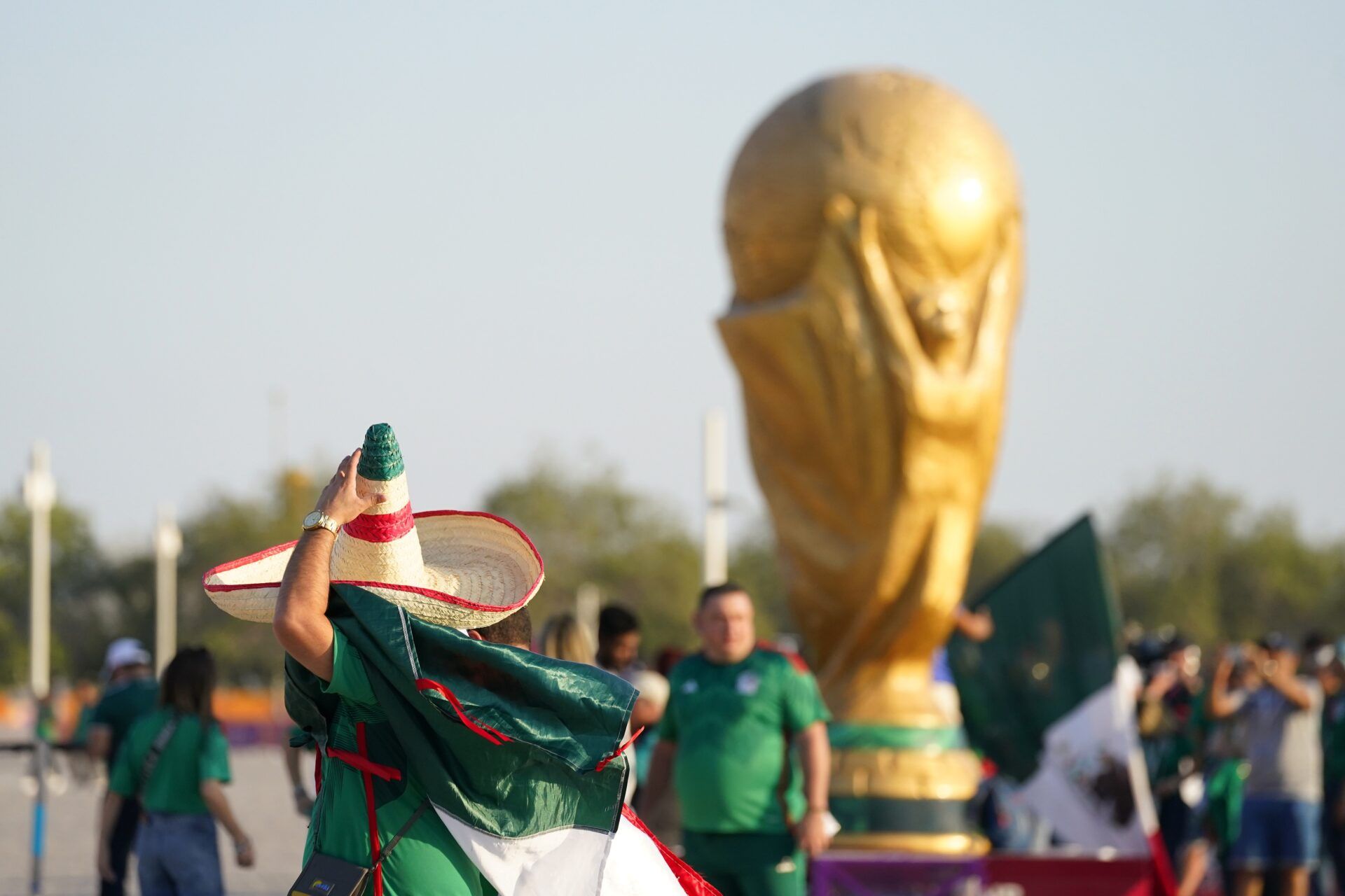 A Mexico fan wearing a sombrero walks past a World Cup trophy replica outside the stadium before the match against Poland during a group stage match at the 2022 World Cup at Ras Abu Aboud Stadium.