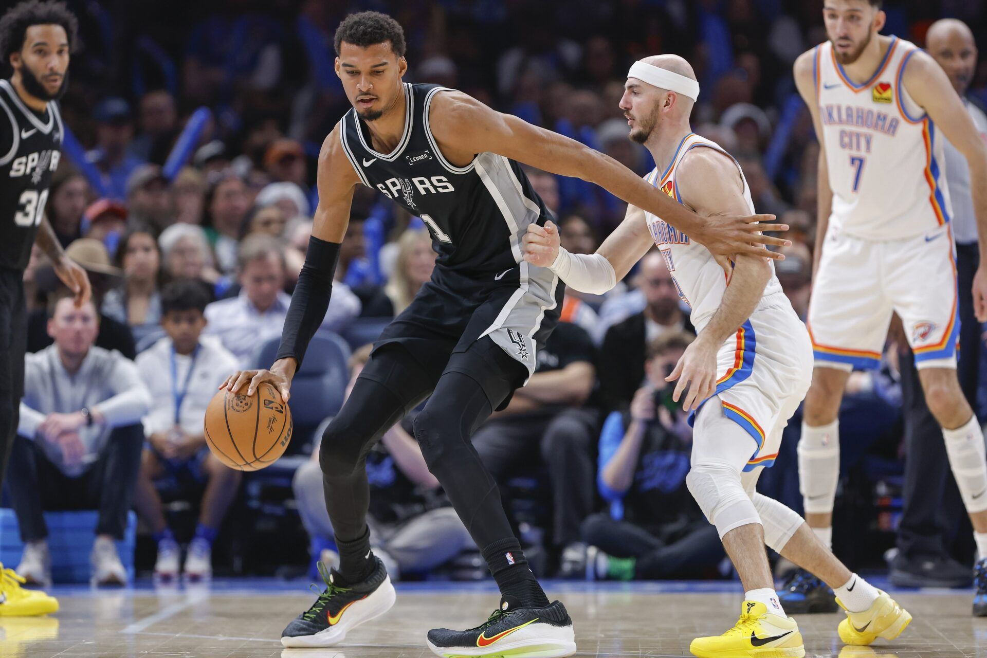 San Antonio Spurs forward Victor Wembanyama (1) moves the ball across the court against Oklahoma City Thunder guard Alex Caruso (9) during the second half at Paycom Center.