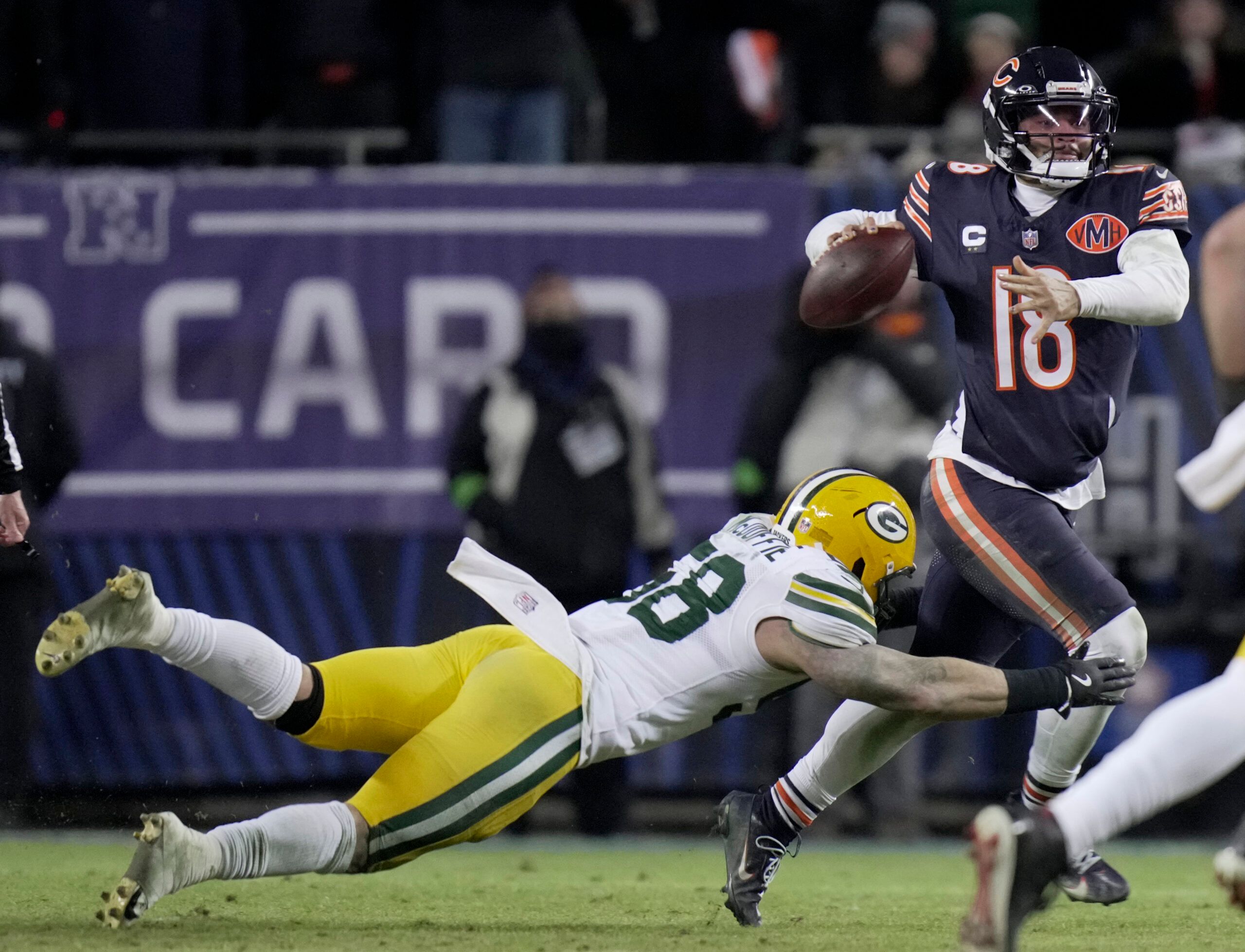 Chicago Bears quarterback Caleb Williams (18) avoids a tackle by Green Bay Packers linebacker Isaiah McDuffie (58) during the fourth quarter of an NFC Wild Card Round game at Soldier Field.