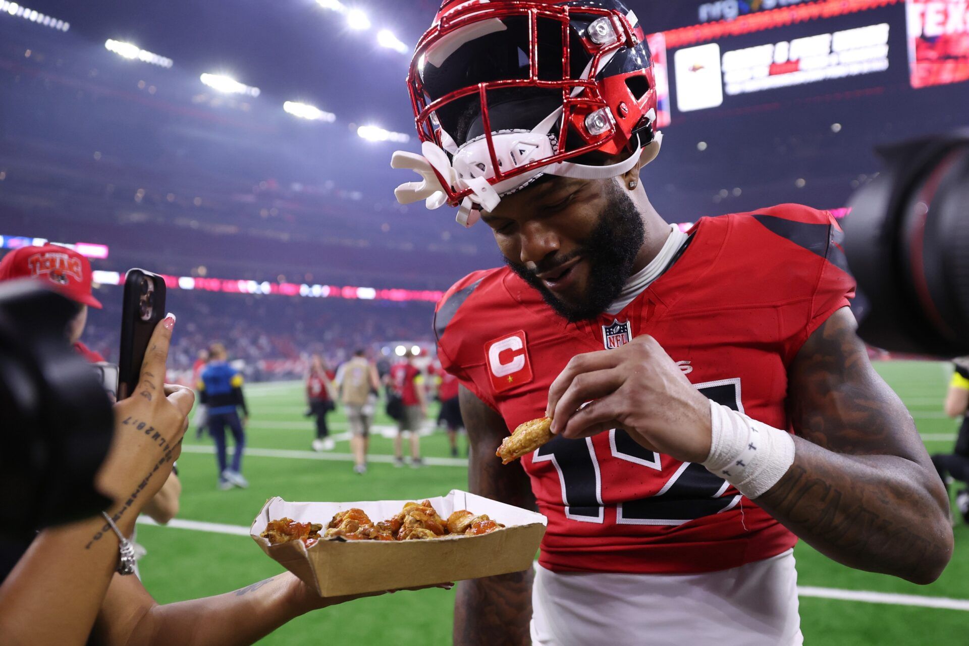 Houston Texans wide receiver Nico Collins (12) eats chicken wings on the field after the game against the Buffalo Bills at NRG Stadium.