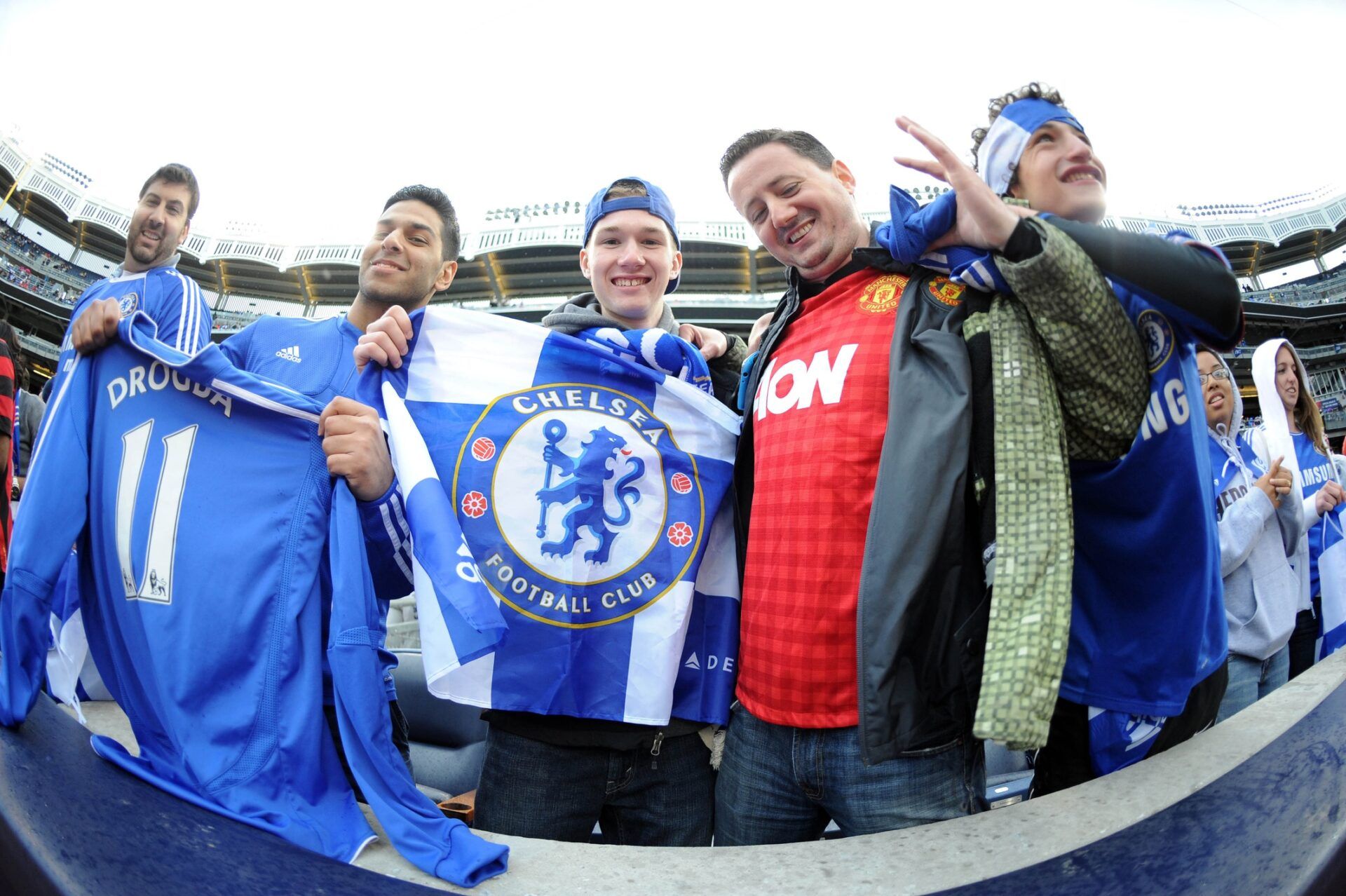 A Manchester United fan (red) cheers with Chelsea fans before the first half against Manchester City at Yankee Stadium. Manchester City won 5-3.