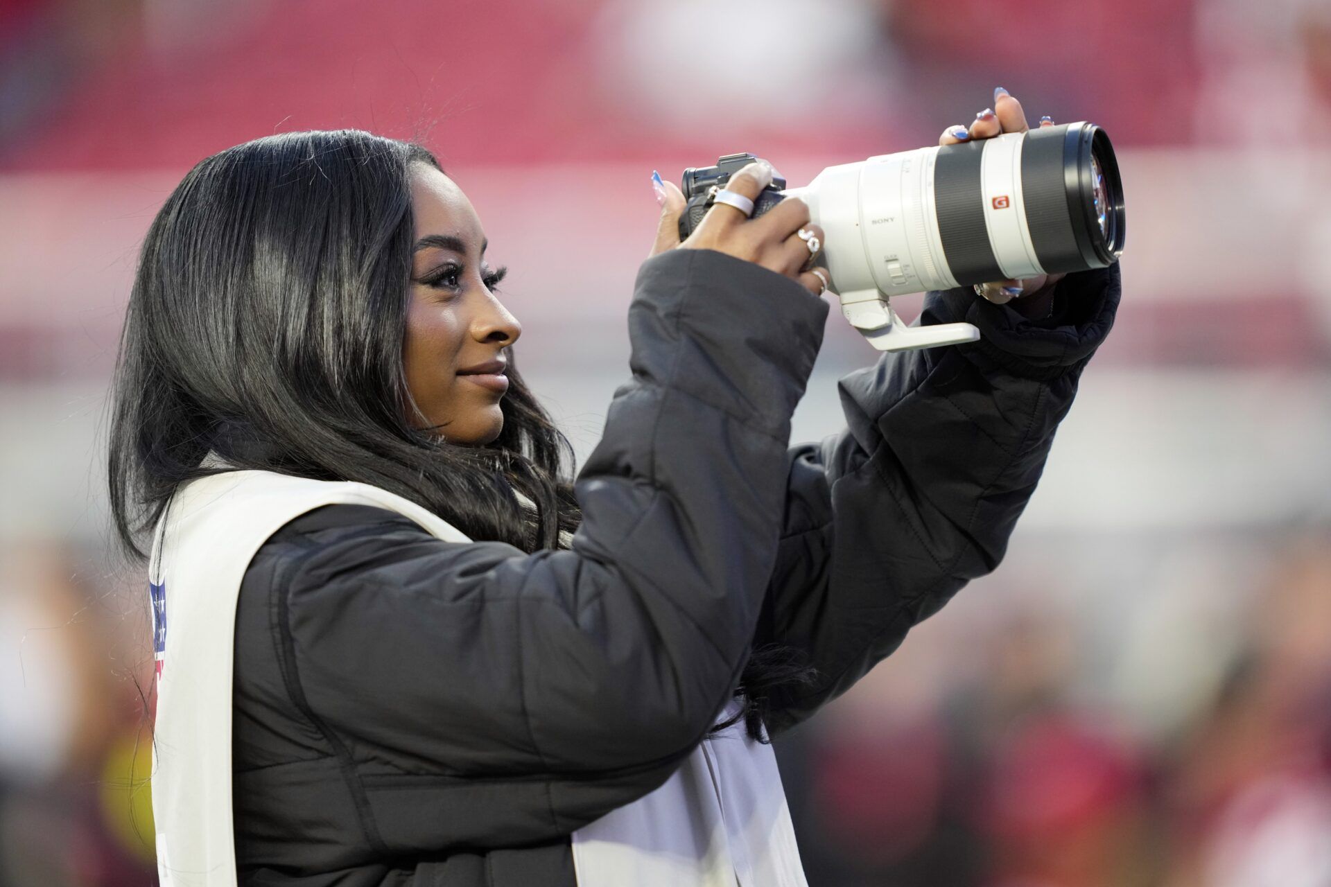 American gymnast Simone Biles takes photographs on the sideline before the game between the San Francisco 49ers and the Chicago Bears at Levi's Stadium.