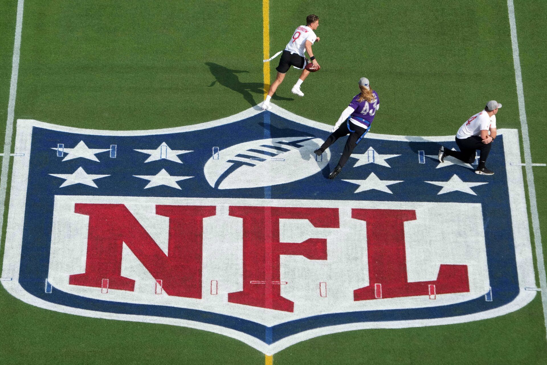 AFC quarterback Joe Burrow of the Cincinnati Bengals (9) is pursued by NFC linebacker Andrew Van Ginkel of the Minnesota Vikings (43) on the NFL shield logo during the 2025 Pro Bowl Games at Camping World Stadium.