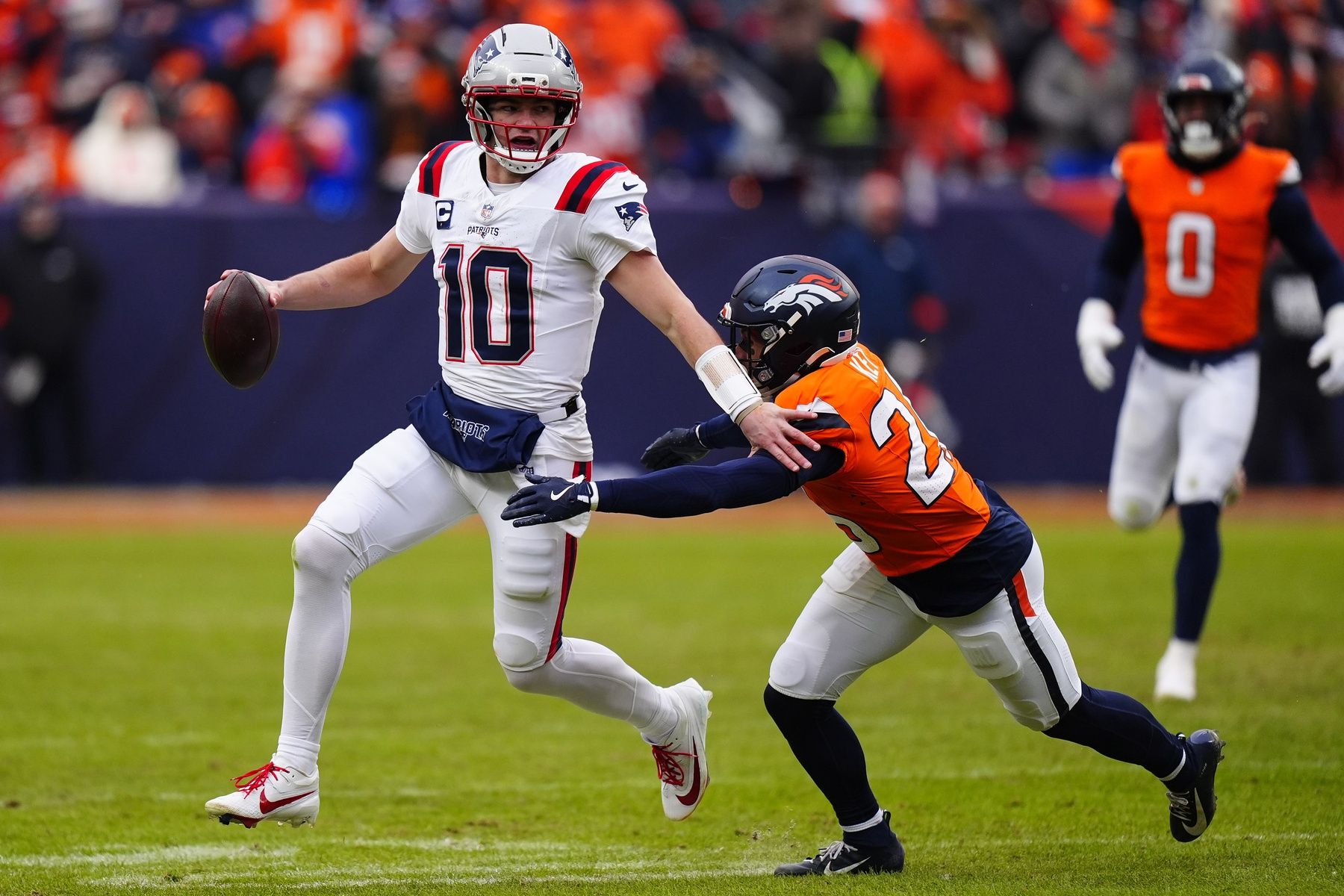 New England Patriots quarterback Drake Maye (10) rushes the ball against Denver Broncos safety Devon Key (26) during the first half in the 2026 AFC Championship Game at Empower Field at Mile High.