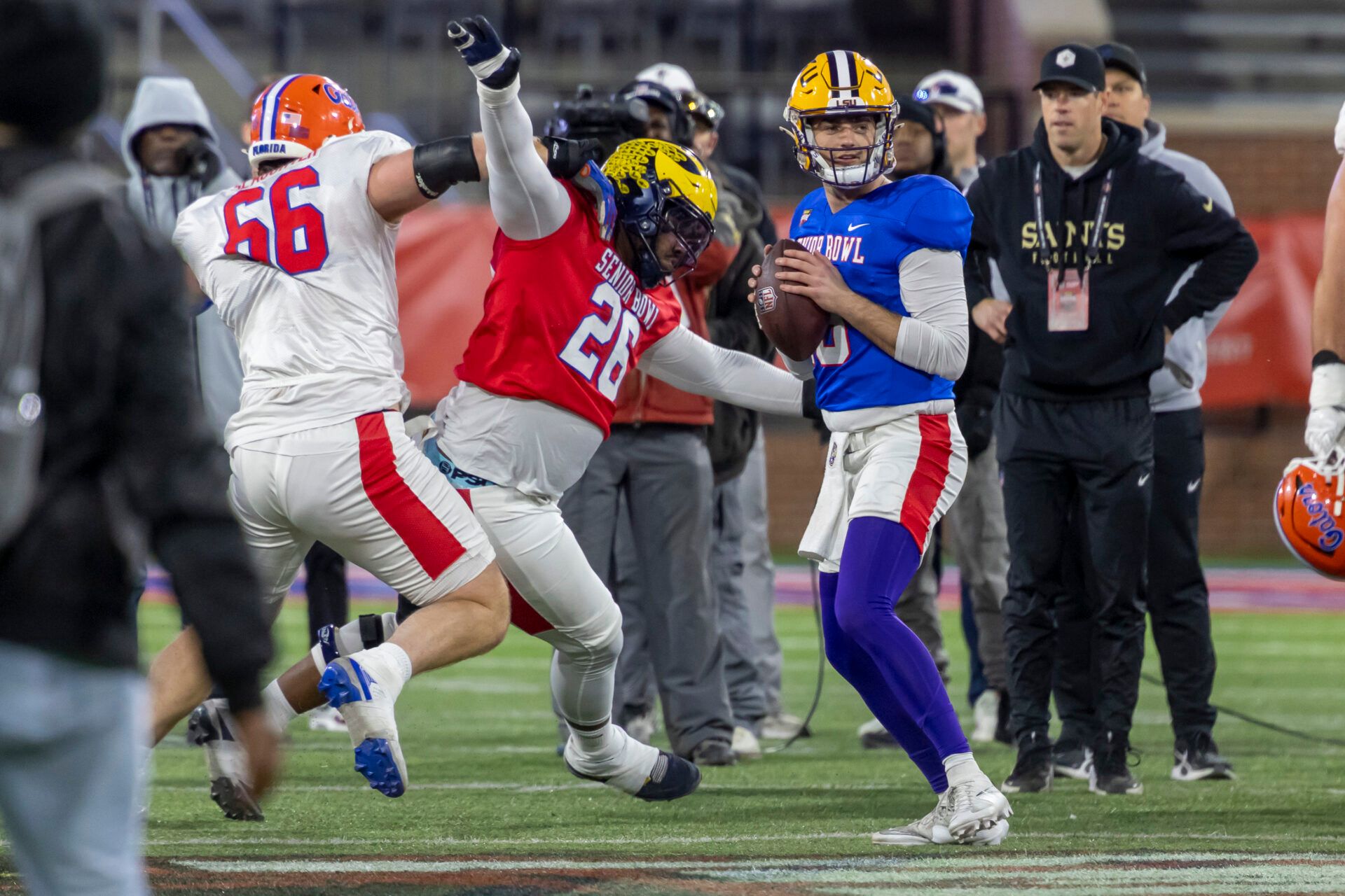 American Team defensive tackle Rayshaun Benny (26) of Michigan battles American Team offensive lineman Jake Slaughter (66) of Florida to get to American Team quarterback Garrett Nussmeier (13) during American Senior Bowl practice at Hancock Whitney Stadium.